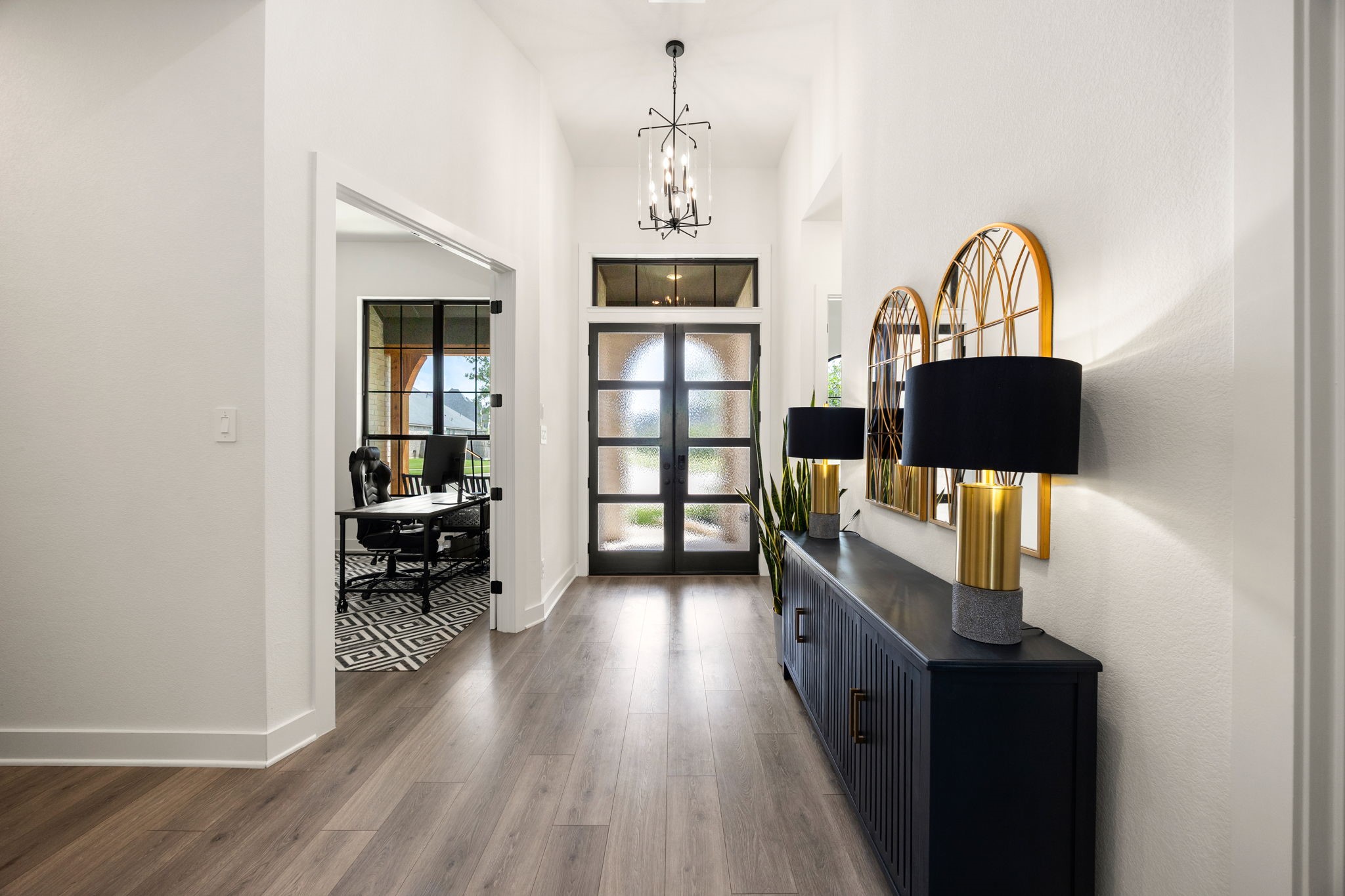 A grand welcome awaits. This bright, airy foyer draws you in with soaring ceilings, elegant statement lighting, and a seamless flow into the heart of the home.