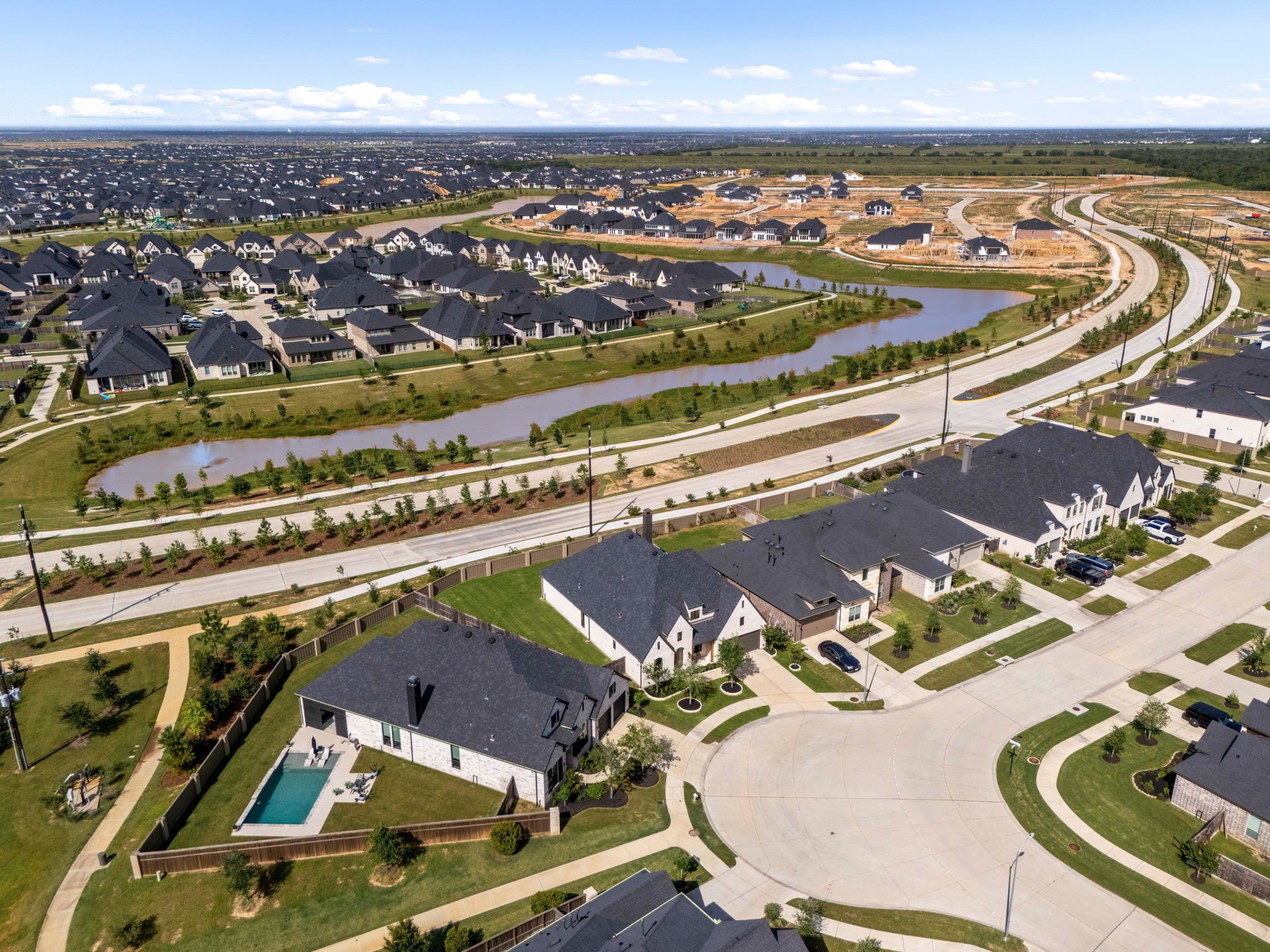 An aerial perspective of Cross Creek West. This stunning bird's-eye view highlights the master-planned neighborhood layout, featuring a winding community waterway, manicured green spaces, and neighborhood walking trails just steps from your door.