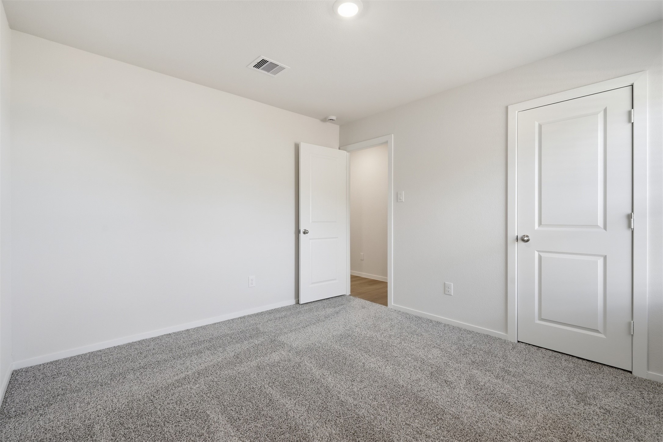 Bright and inviting bedroom featuring plush carpeting, neutral walls, and ample closet space, perfect for a cozy retreat.