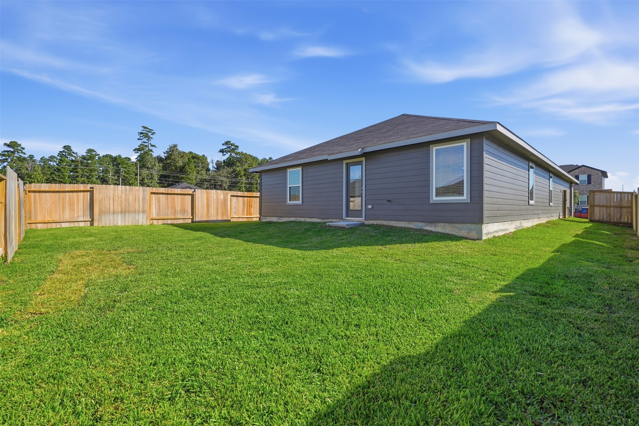 Spacious backyard with lush green lawn and privacy fence, perfect for outdoor activities and relaxation.