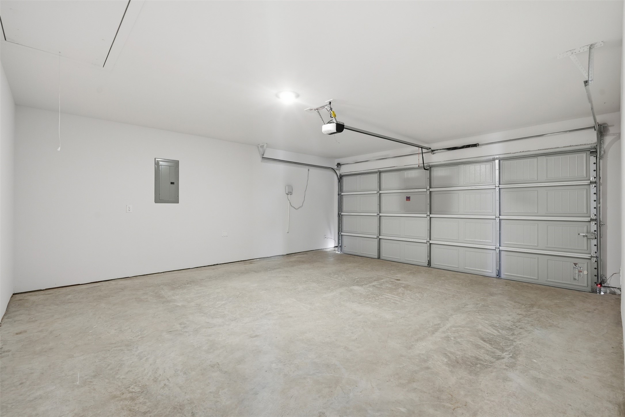 Spacious and clean two-car garage with concrete flooring and ample lighting, perfect for storage or workshop potential.