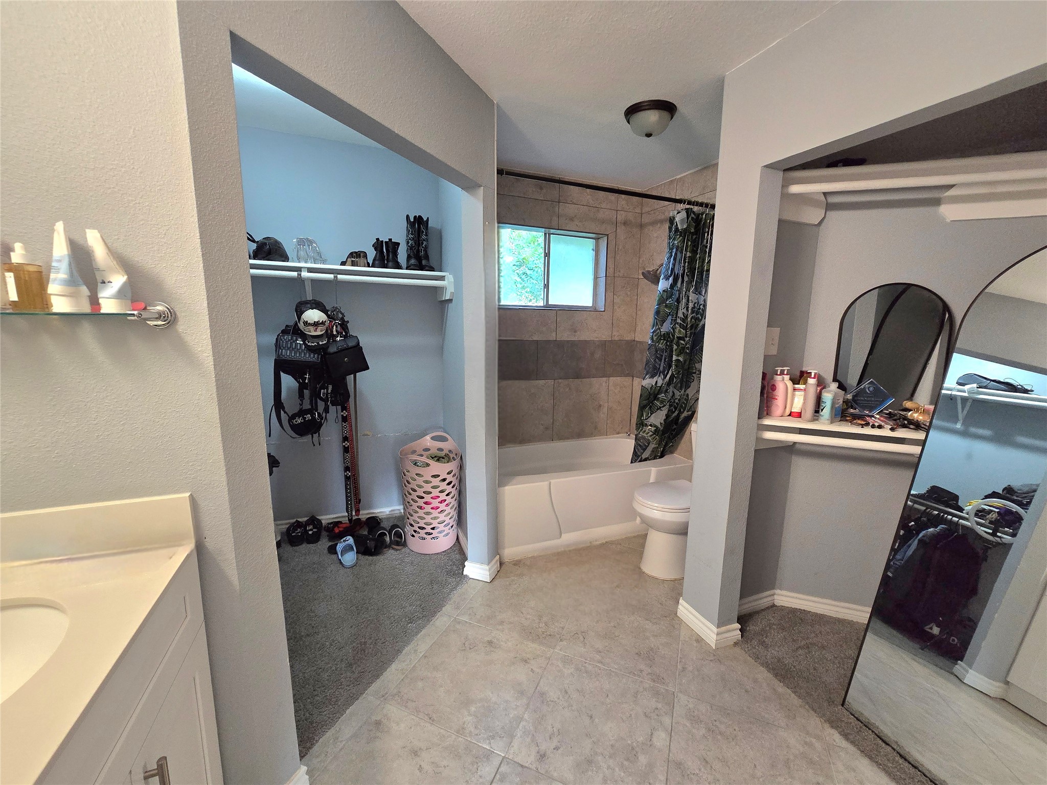 Spacious bathroom with a tiled bathtub and shower, adjacent to a walk-in closet and vanity area for added convenience.