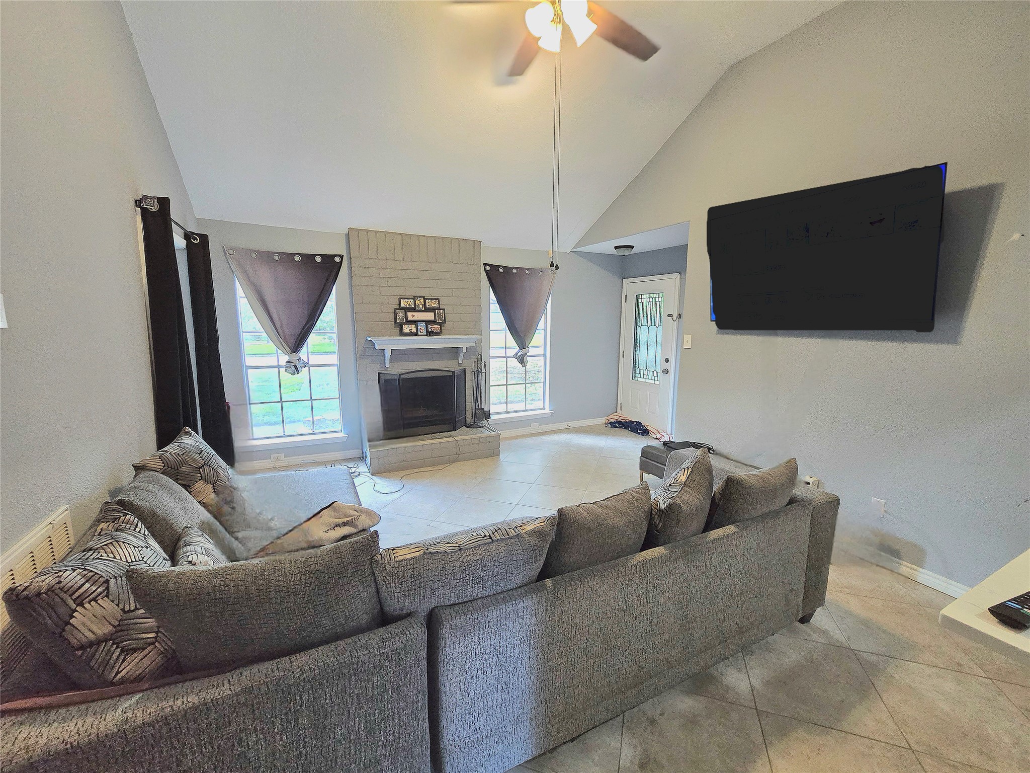 Spacious living room featuring a cozy fireplace, large windows for natural light, and a modern ceiling fan.