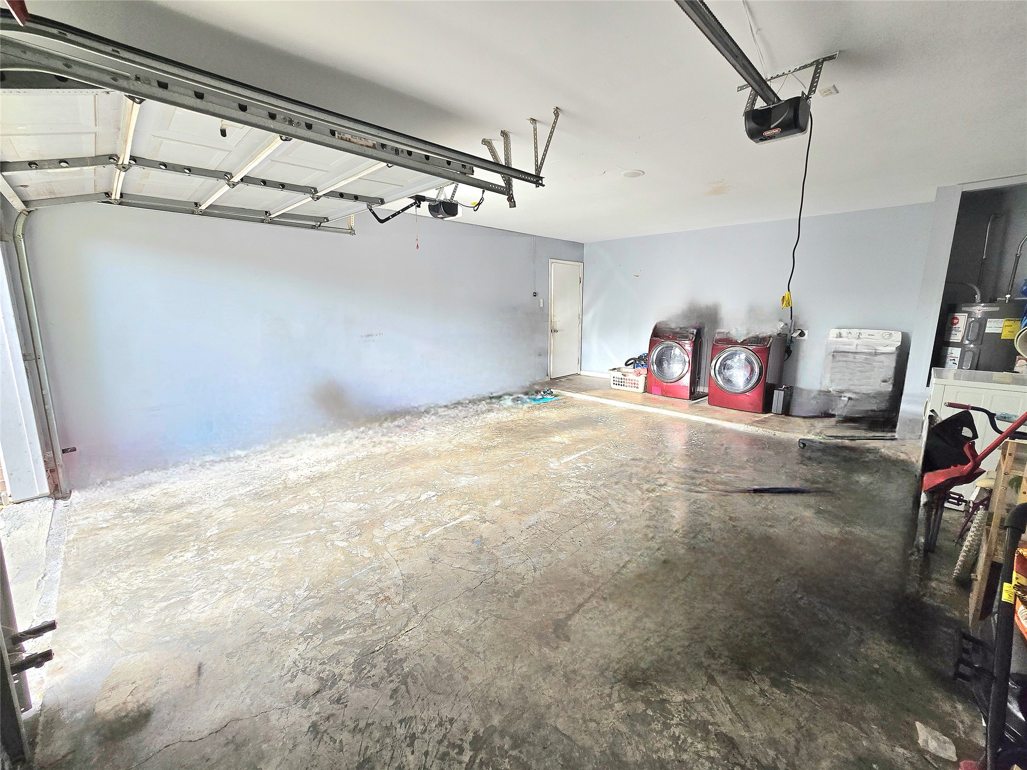 Spacious garage with ample storage space, featuring  washer and dryer hookups for convenient laundry access.