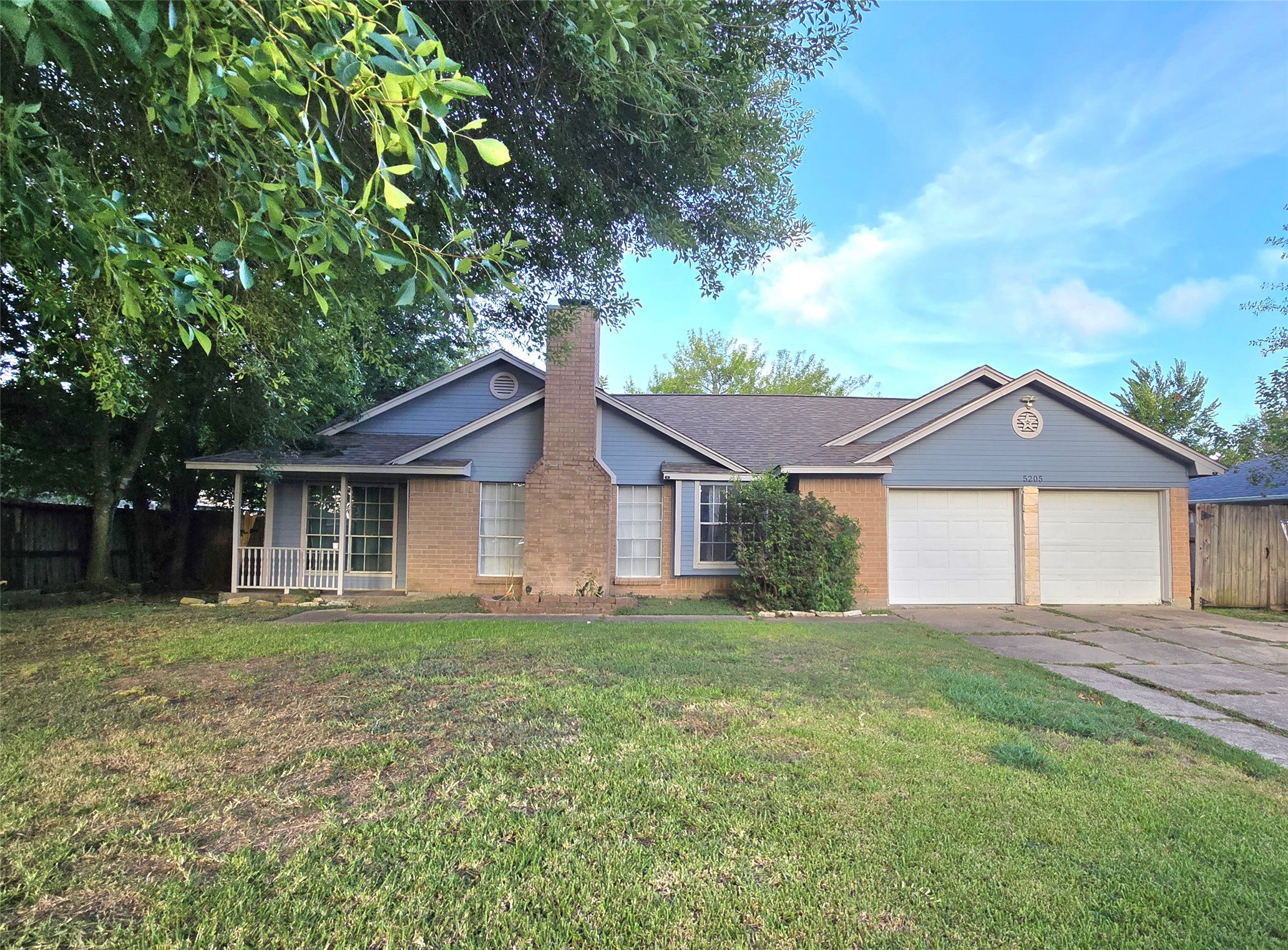 Charming single-story home with a welcoming front porch, spacious driveway, and dual garage. Surrounded by mature trees, this property offers a serene setting.