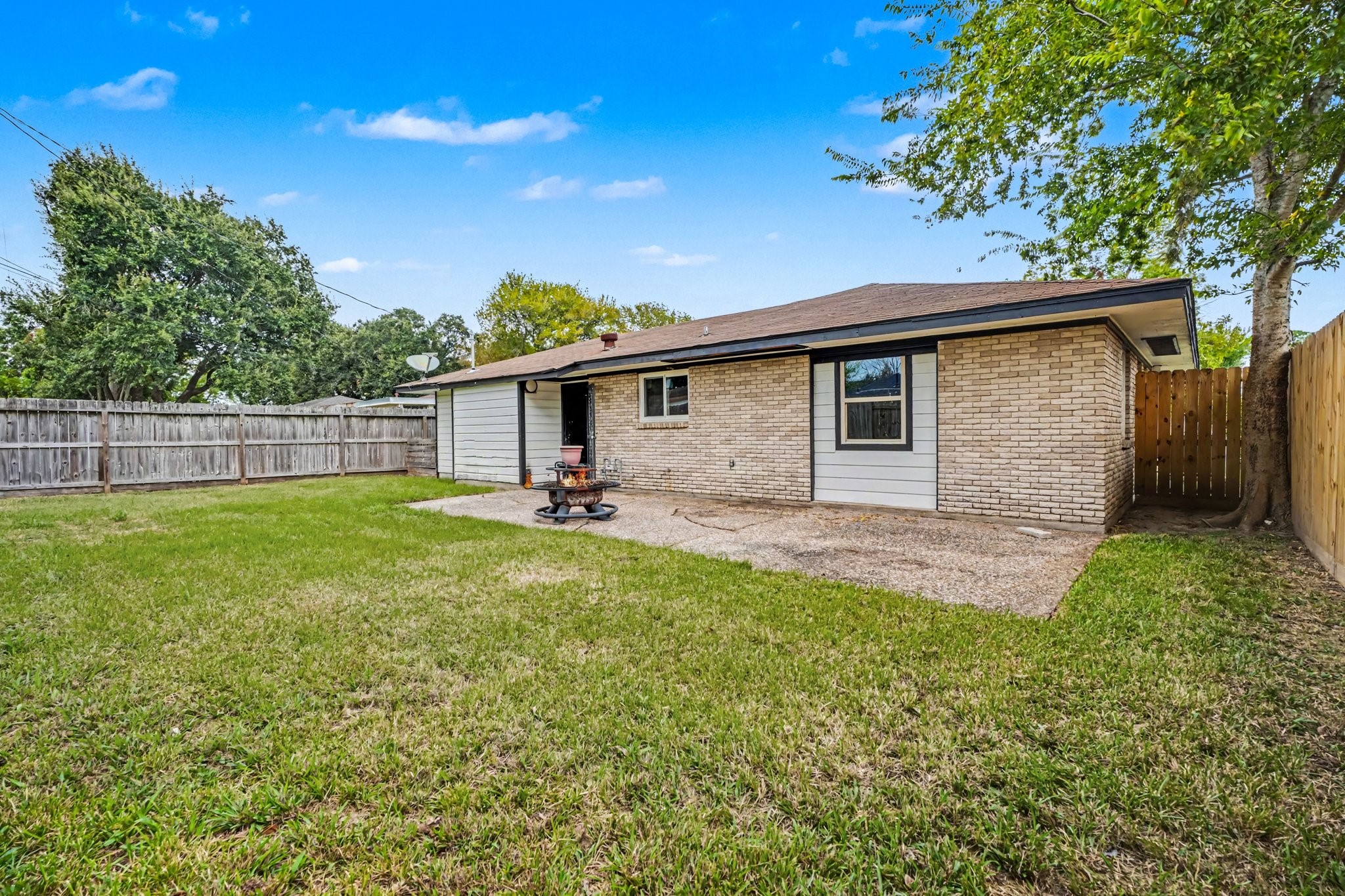 Charming backyard with a spacious lawn, perfect for outdoor activities, bordered by a wooden fence for privacy.