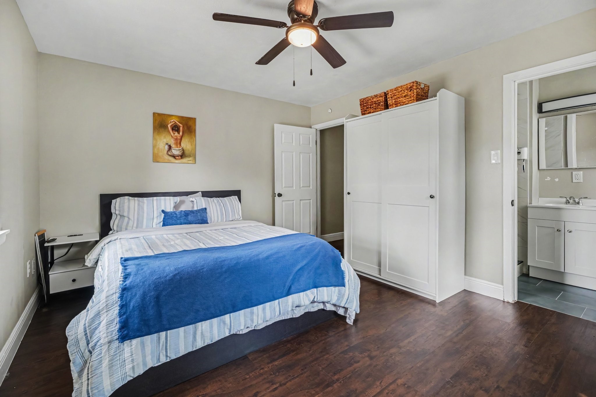 Primary bedroom featuring hardwood floors, ample natural light from two windows, and a ceiling fan for comfort.
