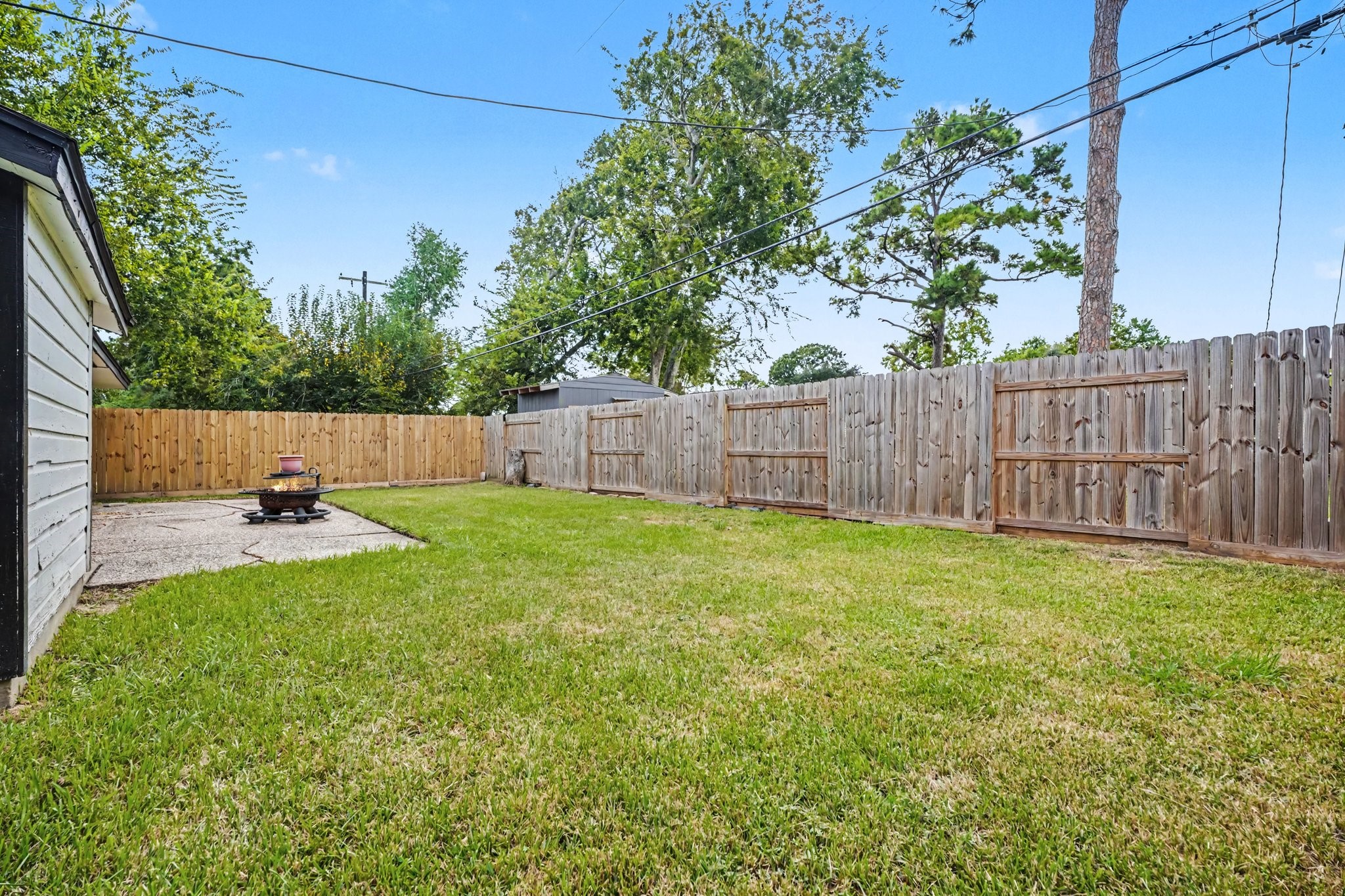 Spacious backyard featuring a lush lawn, privacy fence, and a cozy fire pit area, perfect for outdoor gatherings.