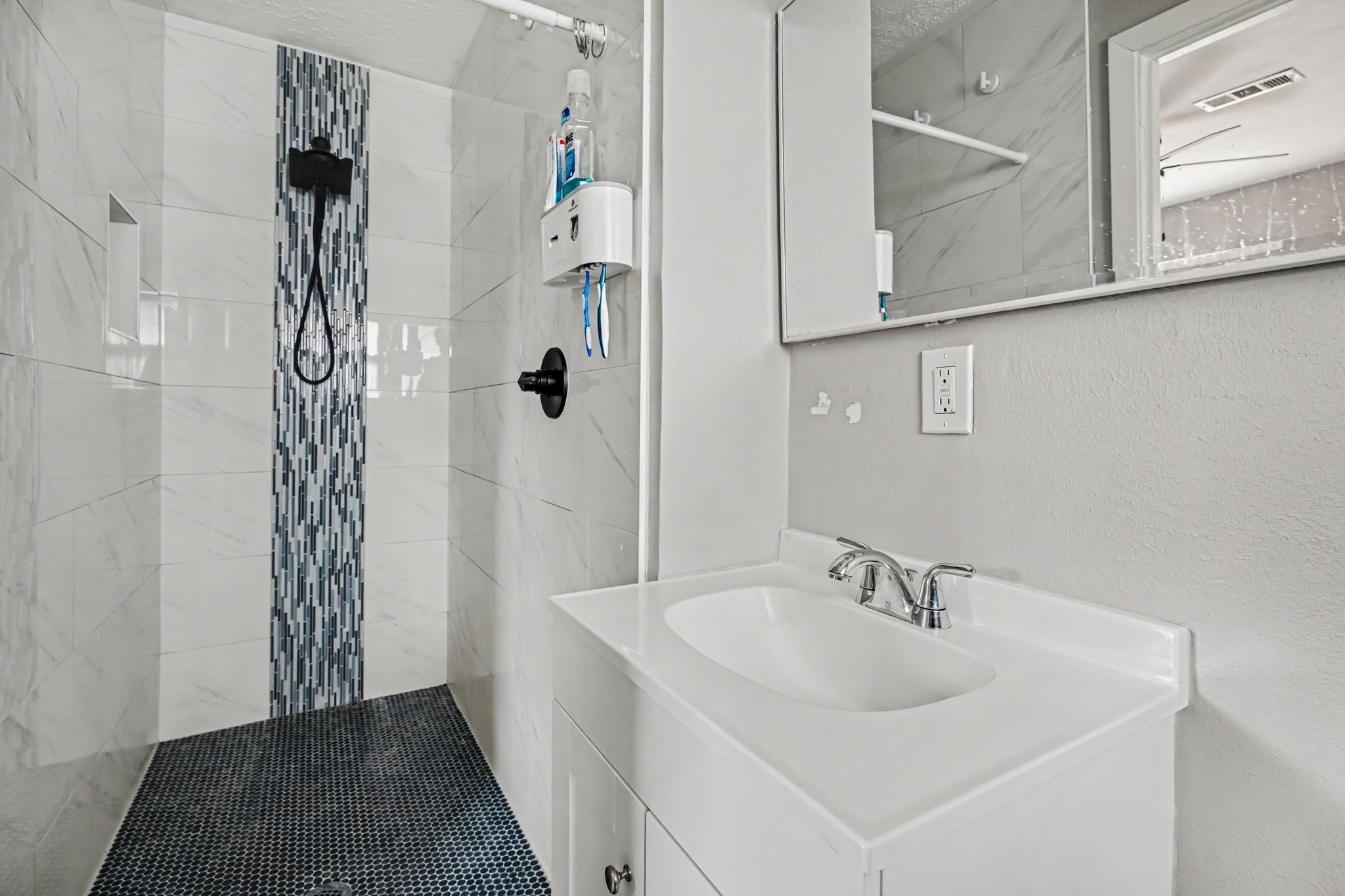 Primary Modern bathroom featuring a sleek walk-in shower with stylish vertical mosaic accents and a chic white vanity with a contemporary faucet.