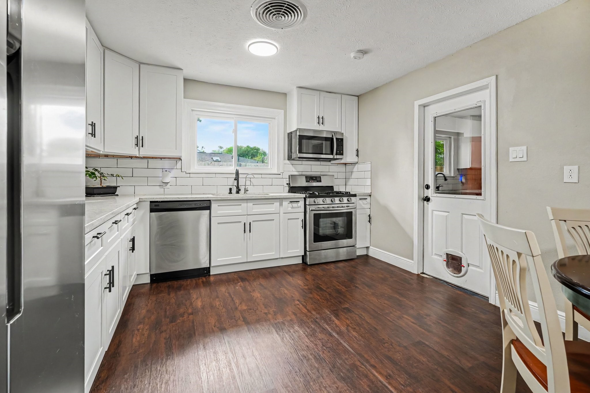 Bright and modern kitchen with sleek stainless steel appliances, elegant white cabinetry, and rich laminate flooring, offering a perfect blend of style and functionality. Bright and modern kitchen with sleek stainless steel appliances, elegant white cabinetry, and rich laminate flooring, offering a perfect blend of style and functionality.