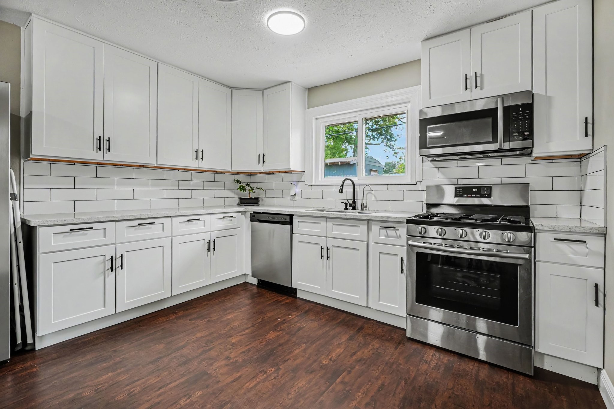 Modern kitchen with sleek stainless steel appliances, subway tile backsplash, and elegant white cabinetry, complemented by laminate floors. Modern kitchen with sleek stainless steel appliances, subway tile backsplash, and elegant white cabinetry, complemented by laminate floors.