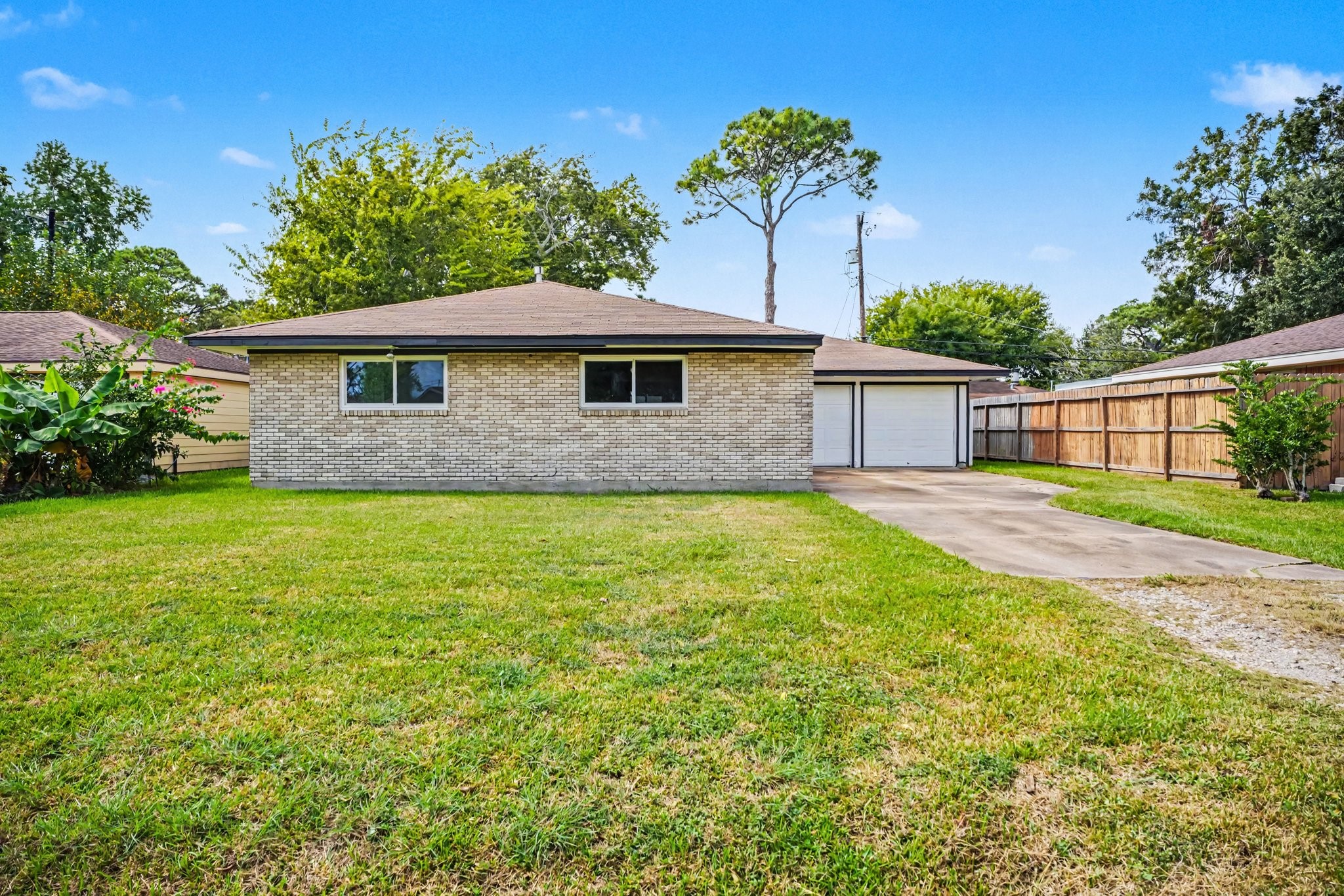 Charming single-story brick home with a spacious front yard and a long driveway leading to a detached garage. Charming single-story brick home with a spacious front yard and a long driveway leading to a detached garage.