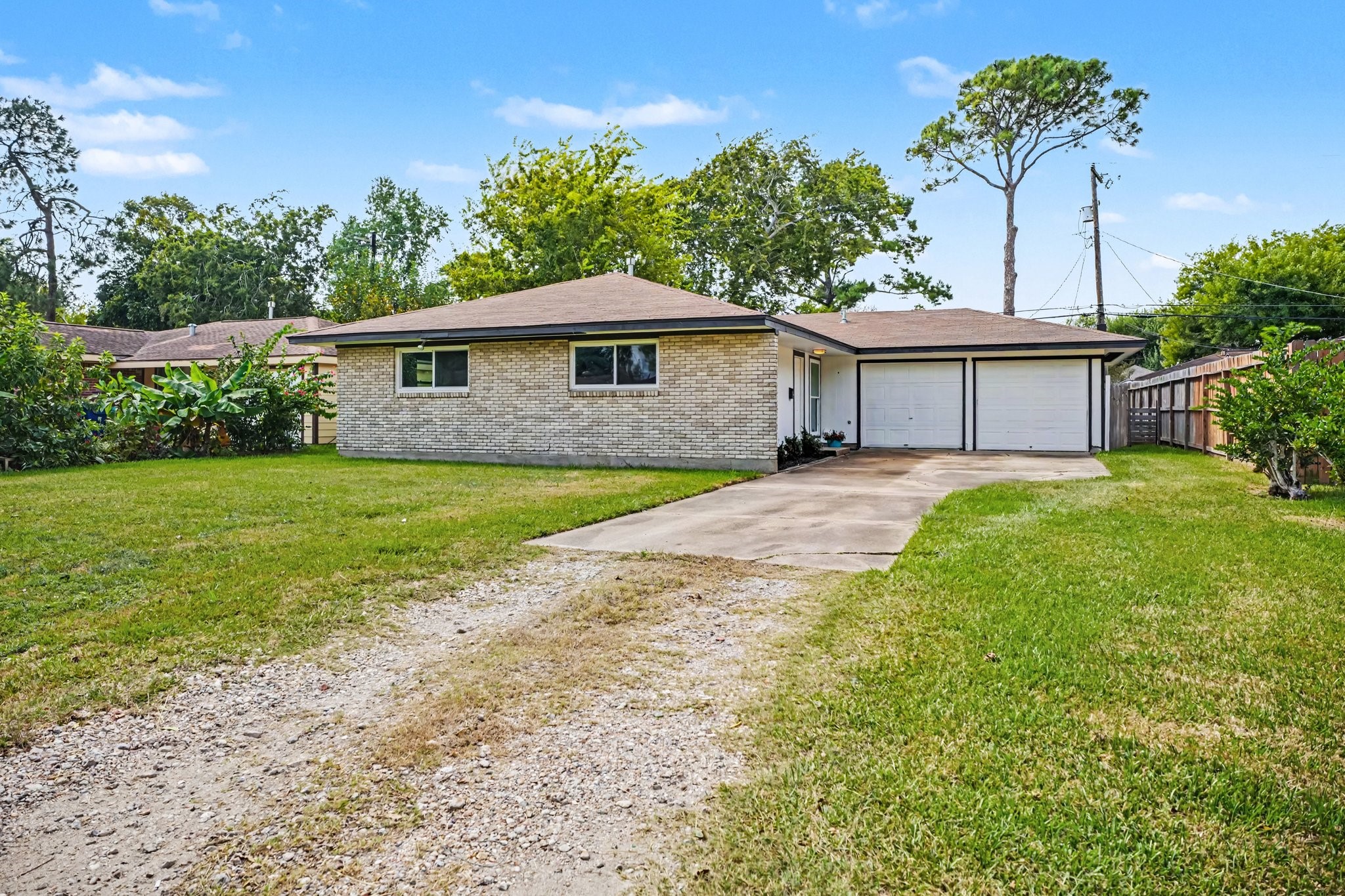 Charming single-story home with a spacious front yard, two-car drive way and garage, and brick exterior, nestled in a serene neighborhood.