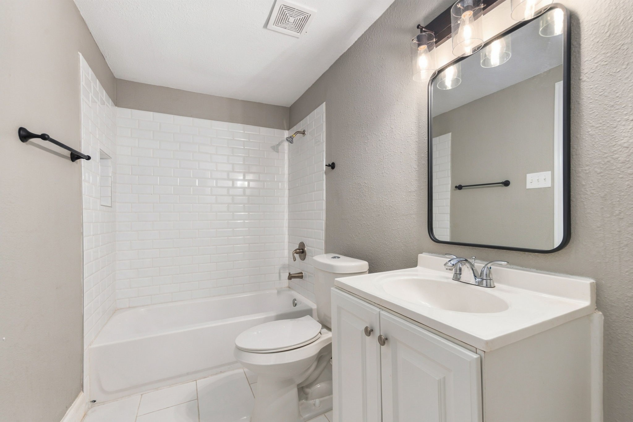 Modern bathroom featuring a sleek vanity with a contemporary mirror, complemented by a classic white bathtub and subway tile surround for a stylish touch.