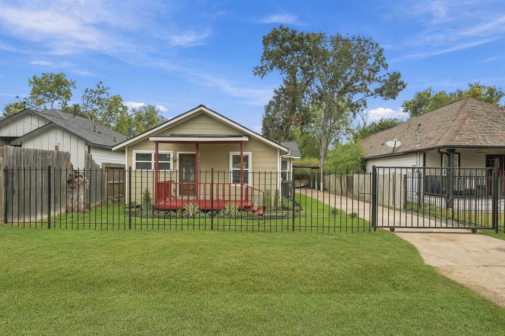 Charming single-story home with a welcoming front porch, neatly fenced yard, and a long driveway leading to ample parking.