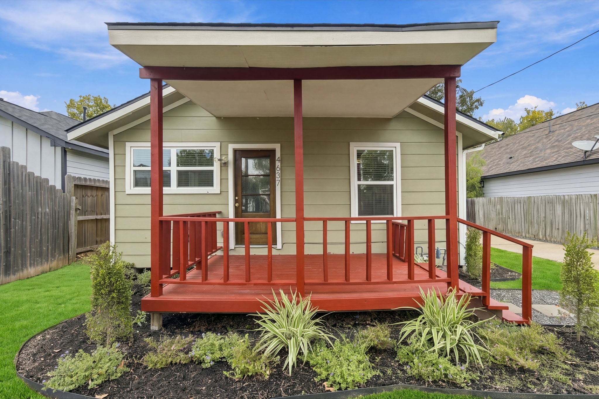 Charming single-story home with a welcoming red front porch, set amidst well-maintained landscaping.