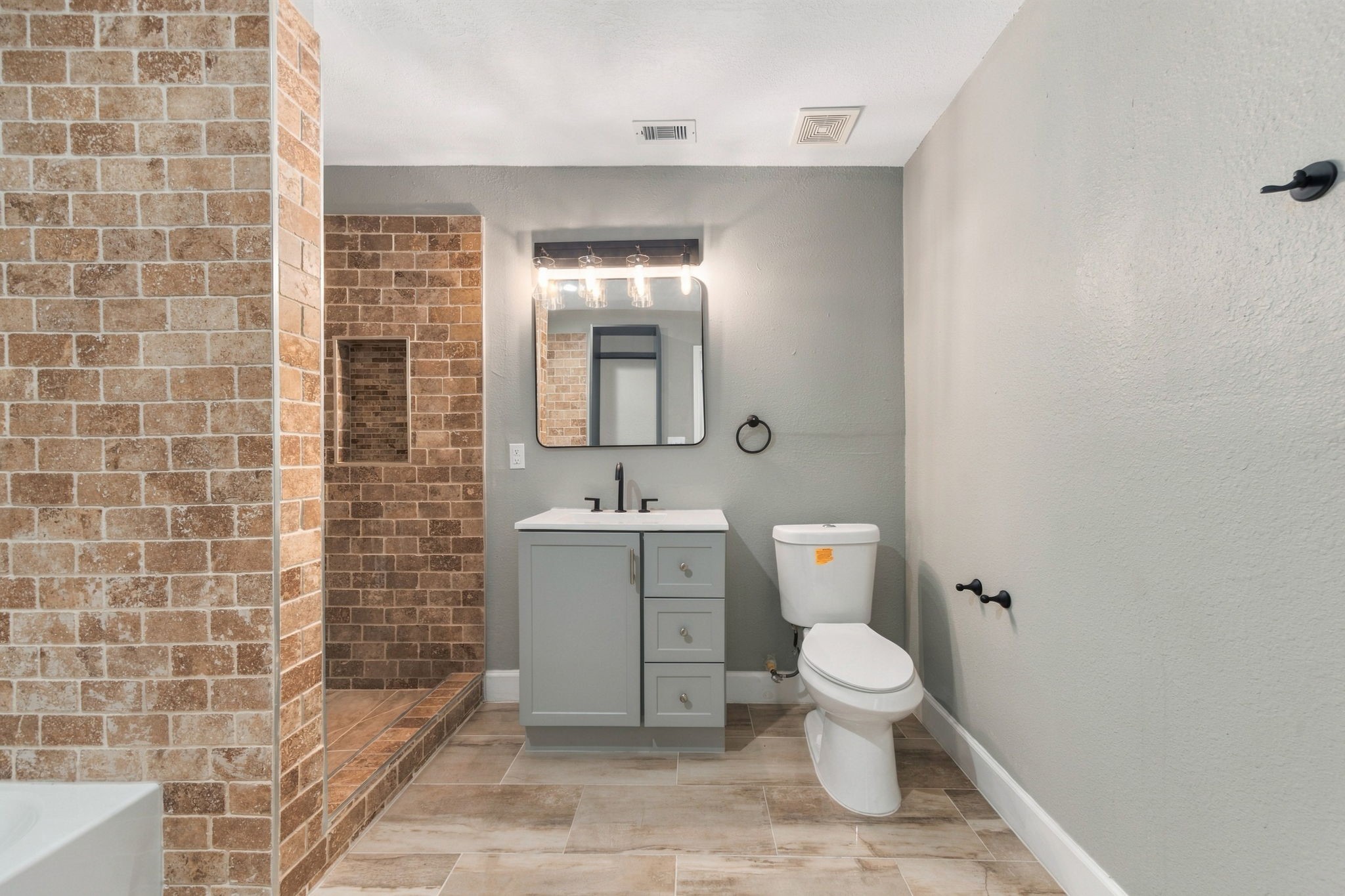Stylish bathroom with a modern vanity, sleek fixtures, and a spacious walk-in shower featuring elegant brick-style tilework.