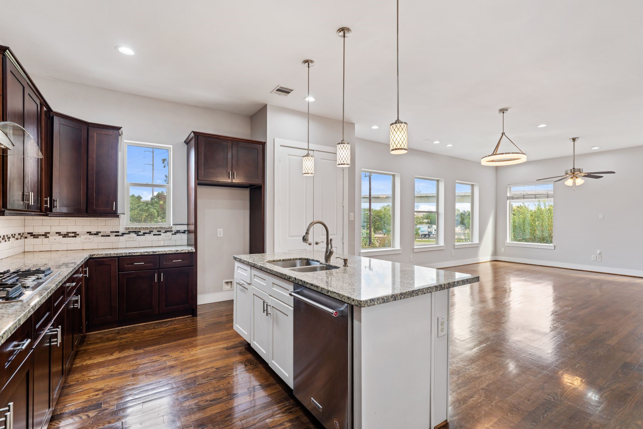 Open kitchen with wood cabinetry, granite countertops, a large island with bar seating, and stainless steel appliances.