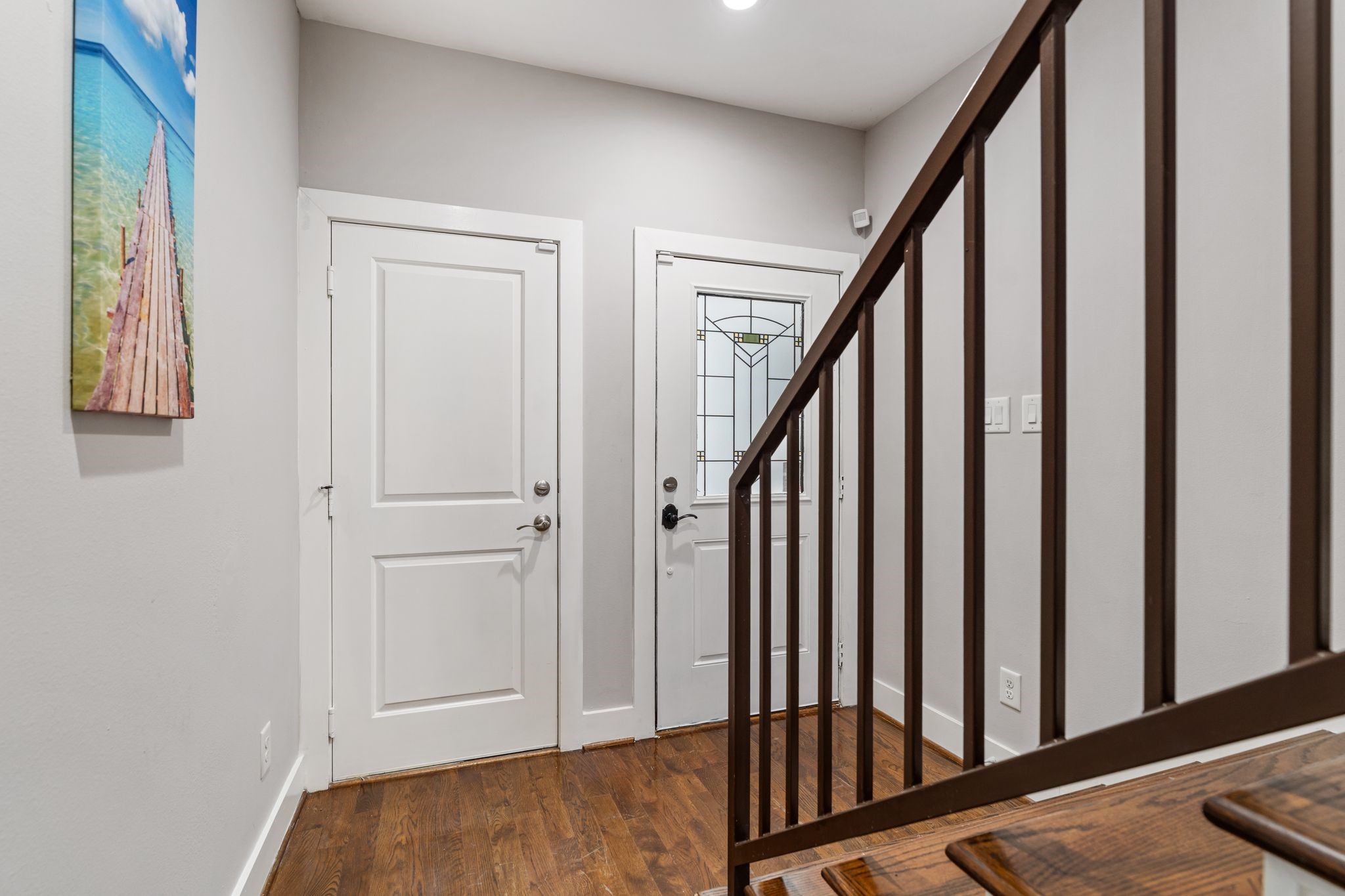 Front entry featuring hardwood floors, a glass-paneled front door, and staircase access to the upper levels.