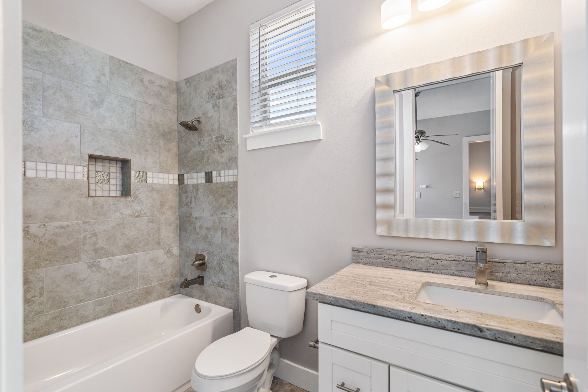 Secondary bedroom en-suite bathroom with granite countertops.