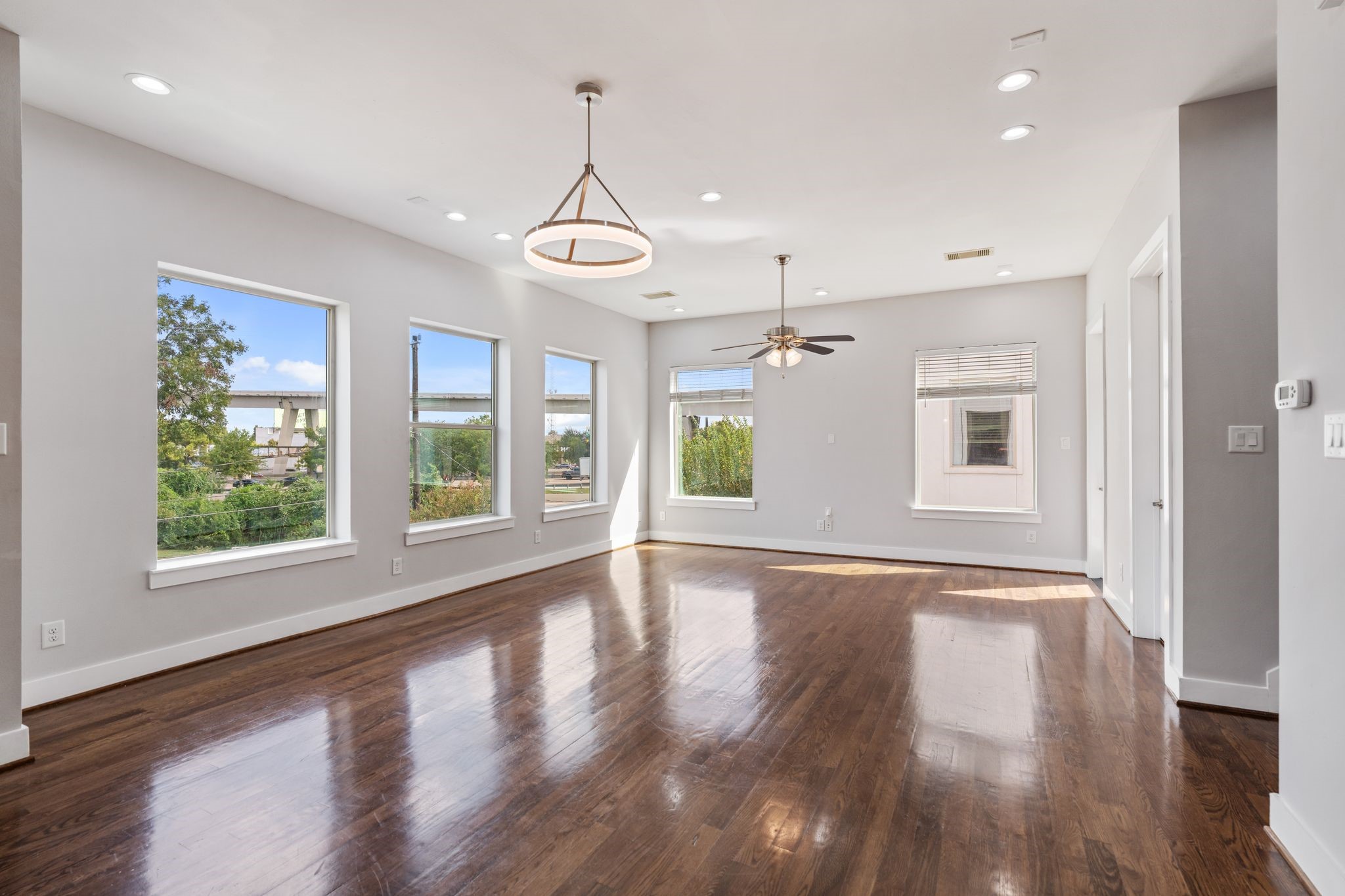 Spacious living area with hardwood floors, recessed lighting, large windows, and an open layout.
