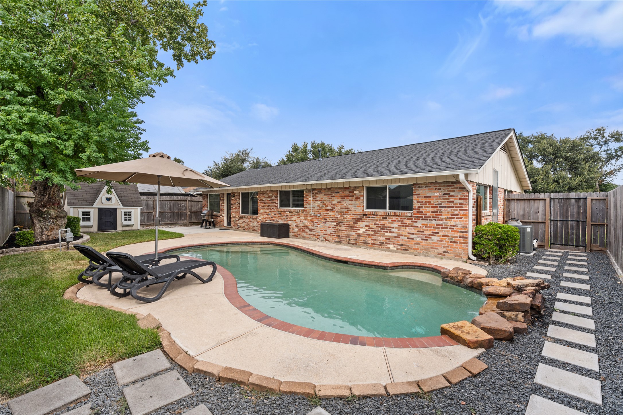 Private backyard retreat featuring a sparkling pool surrounded by lush greenery - perfect for relaxation and entertaining on hot Houston days.