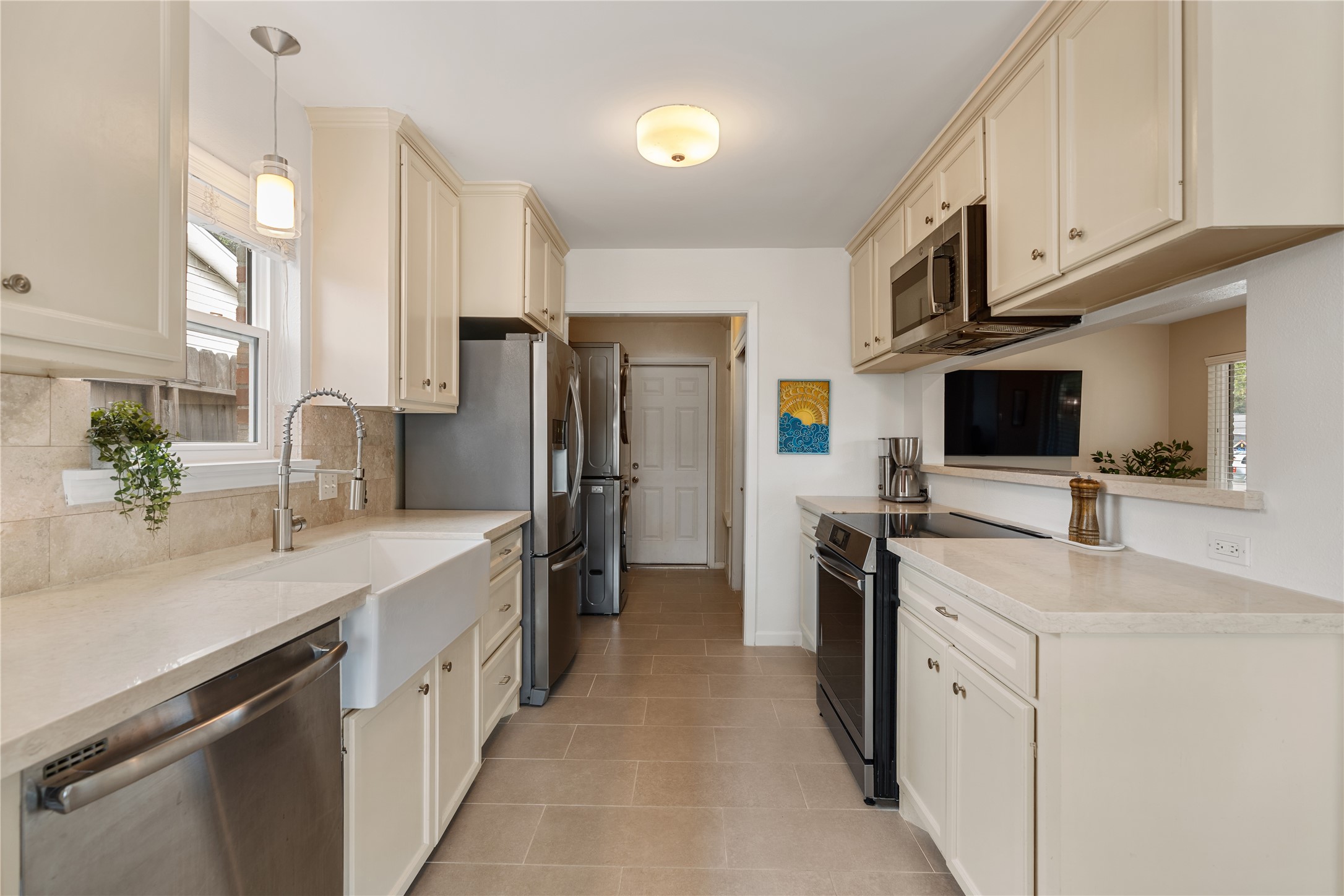Bright and inviting kitchen featuring modern stainless steel appliances, sleek countertops, and window overlooking porcelain farmhouse sink. Bright and inviting kitchen featuring modern stainless steel appliances, sleek countertops, and window overlooking porcelain farmhouse sink.