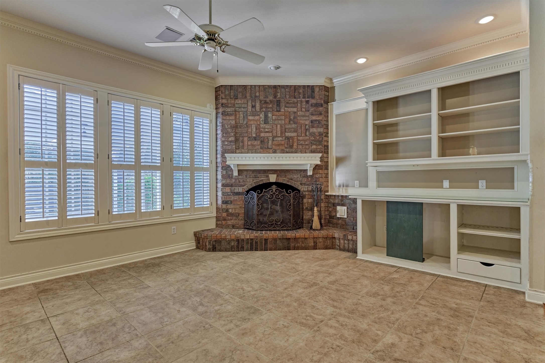 Gather around the gas log fireplace in this downstairs family room, open to the kitchen through an arched pass-through. Large shuttered windows overlook the backyard and fill the room with light. Built-in shelves and cabinets give you room for a TV, books, and dcor, and the mix of tile and hardwood floors is easy to live in.