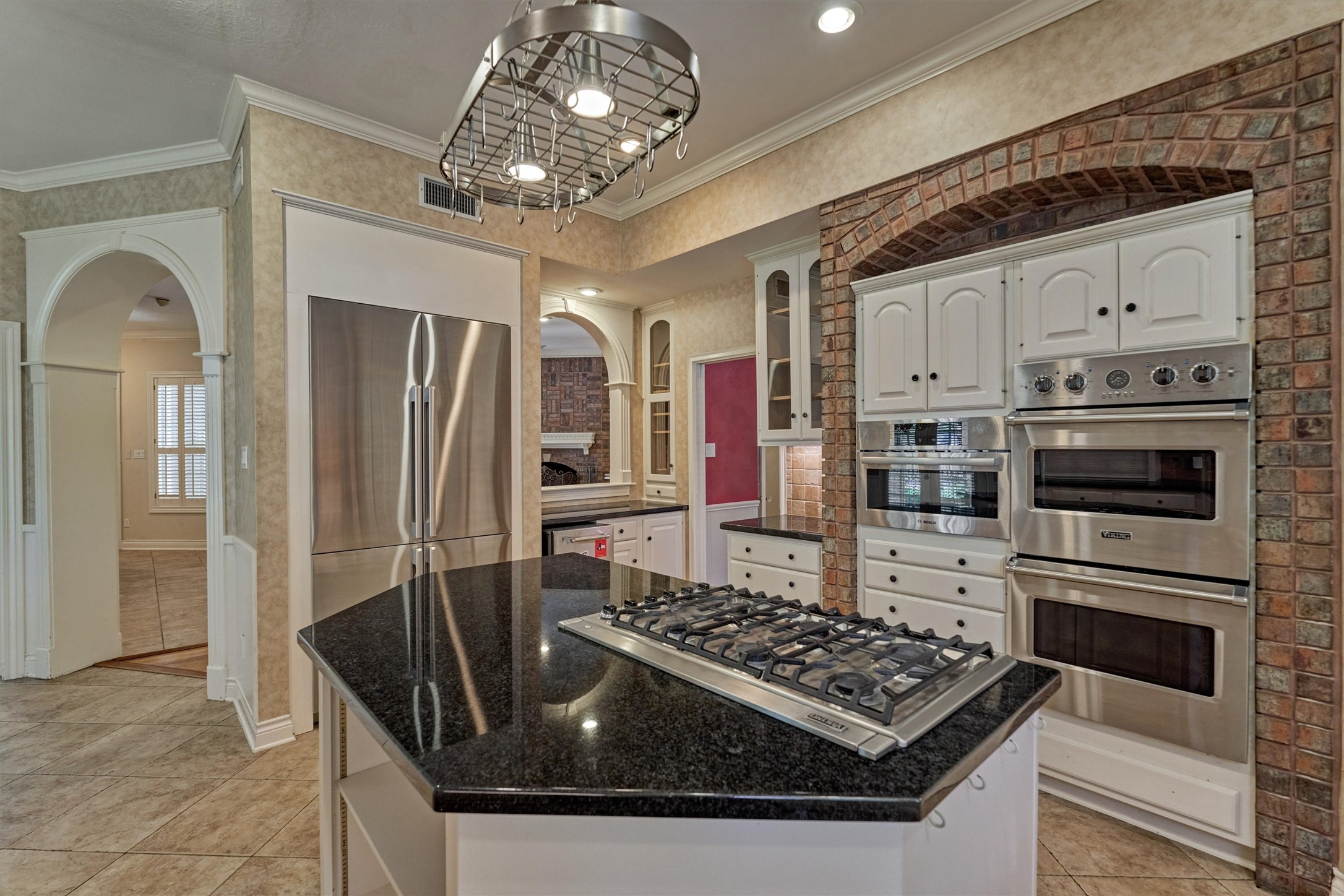 Cook and entertain in style in this chefs kitchen, featuring granite countertops, Viking stainless appliances, and a large island with a gas cooktop. Tile floors, plenty of cabinet storage, and an open sightline to the family room keep the cook connected to the action. The brick-arched oven niche adds warmth and character.