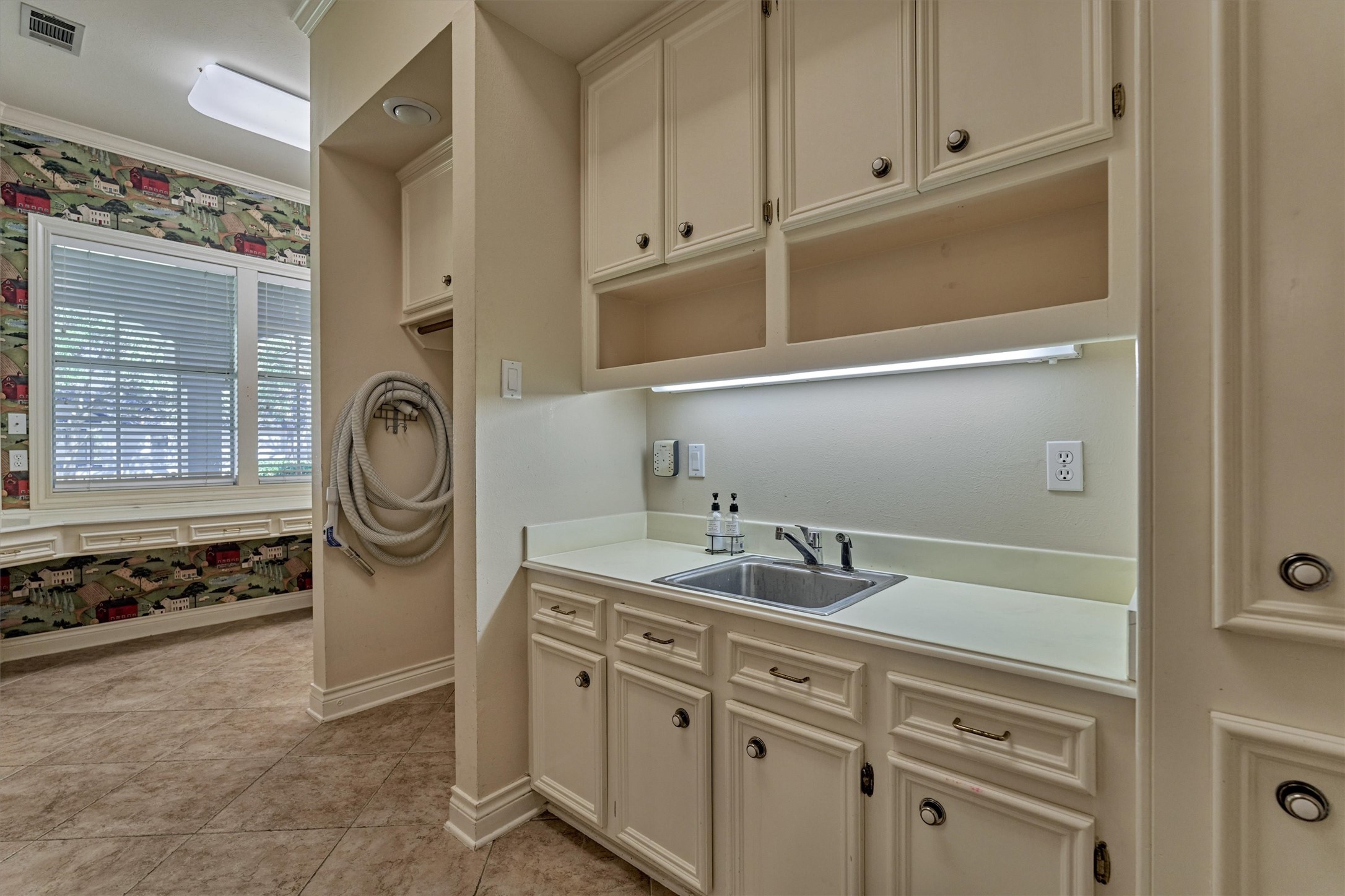 Laundry day gets easier in this huge utility room. Tons of cabinet storage, a utility sink, and plenty of counter space keep everything organized, while the desk area makes it a handy spot for crafts, bills, or homework. Washer and dryer hookups are ready to go, and theres room for an extra refrigerator or freezer. Natural light from the window and tile floors make it bright and easy to maintain.