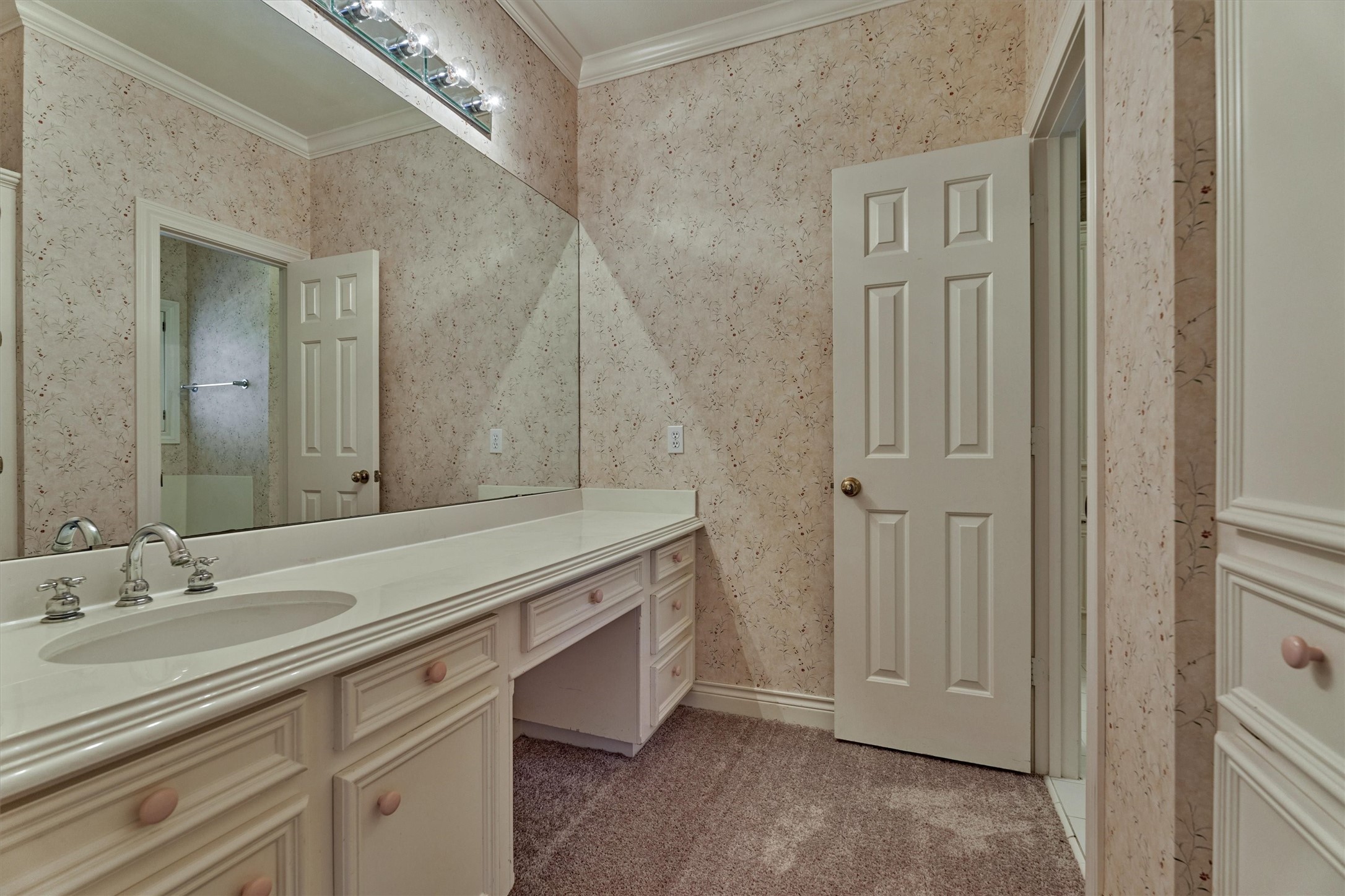 No more fighting over the sink. Each bedroom has its own sink and counter, and this second one offers plenty of drawer and cabinet space plus a seated makeup or grooming spot. A wide mirror and bright lighting make getting ready easy, and the shared bath with tub and shower is steps away through a separate door.