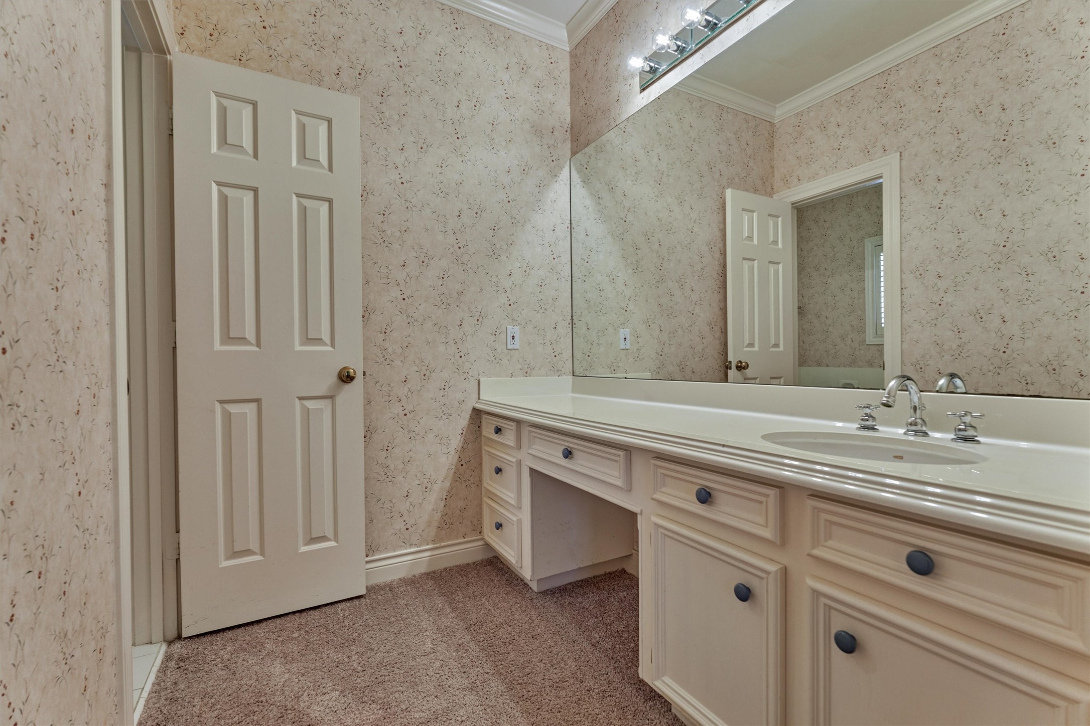 Mornings run smoothly in this shared bath setup, where each bedroom has its own sink and counter. This side offers a long vanity with plenty of drawers and cabinets, plus a seated makeup or grooming area. A wide mirror and bright lighting make getting ready easy, and the separate bath area keeps privacy where it counts.