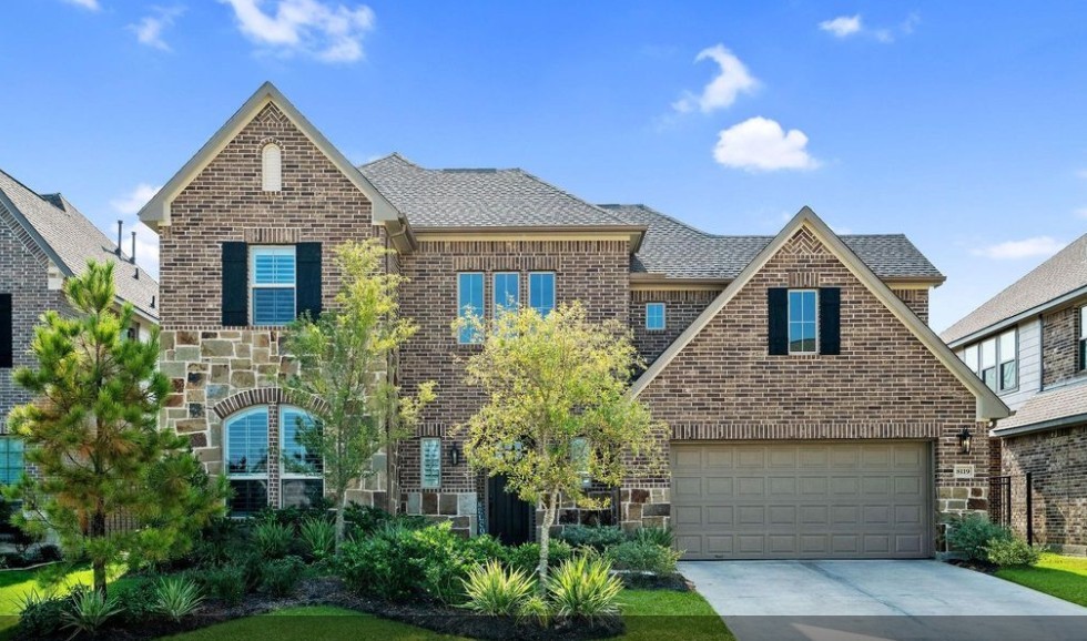 Stunning two-story brick home with elegant stone accents, beautifully landscaped front yard with landscape lighting, and a spacious 3.5 tandem car garage.