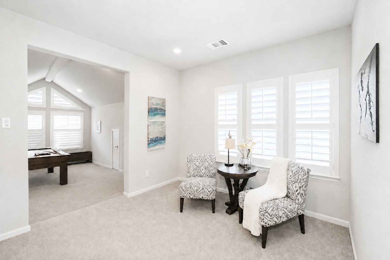Take a look at this sitting area with plush carpeting and large windows offering ample natural light, seamlessly connected to the game room.
