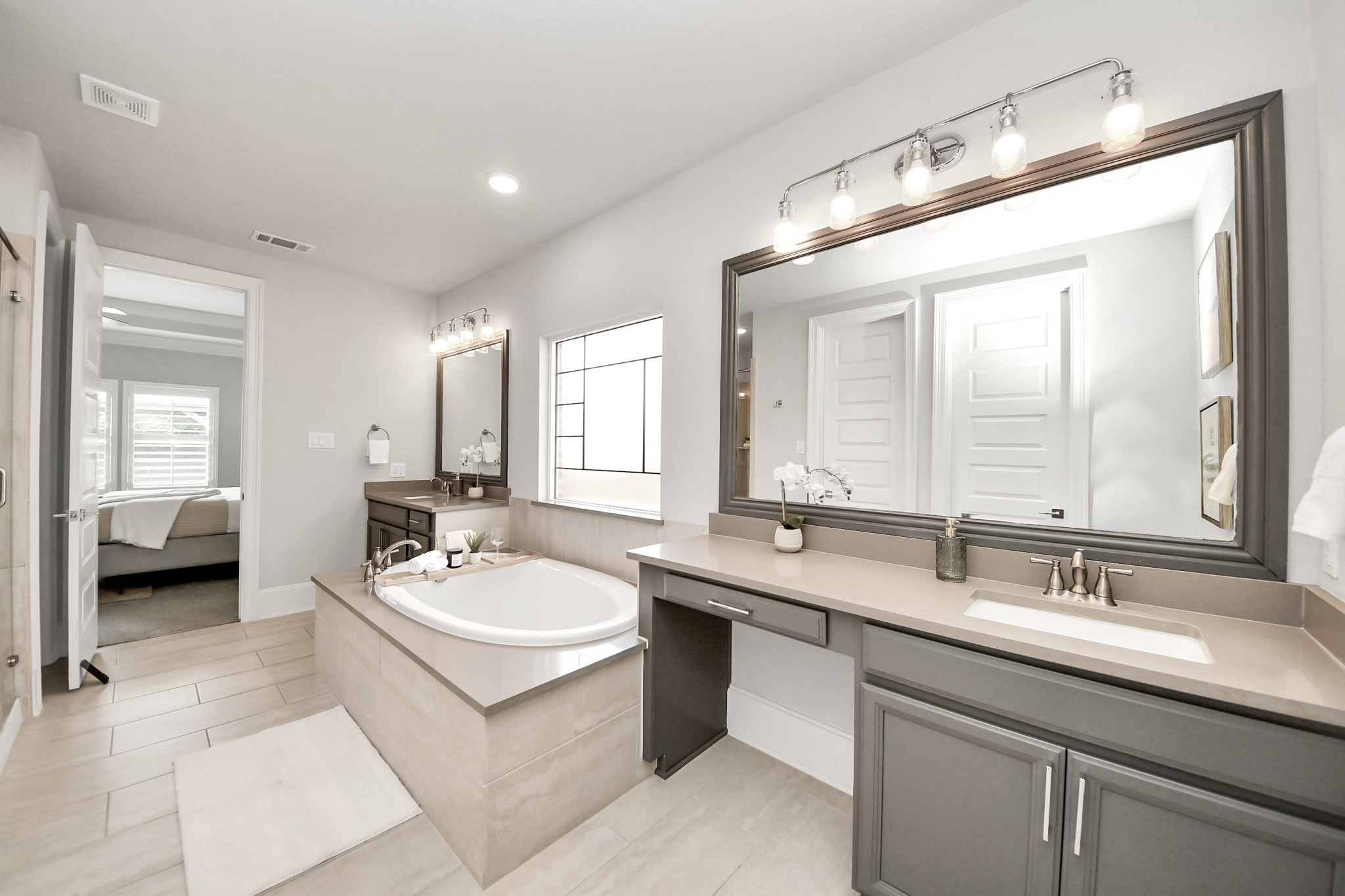 Another view of the primary bathroom with upgraded lighting, framed mirrors, an enclosed toilet area, and 2 closets.