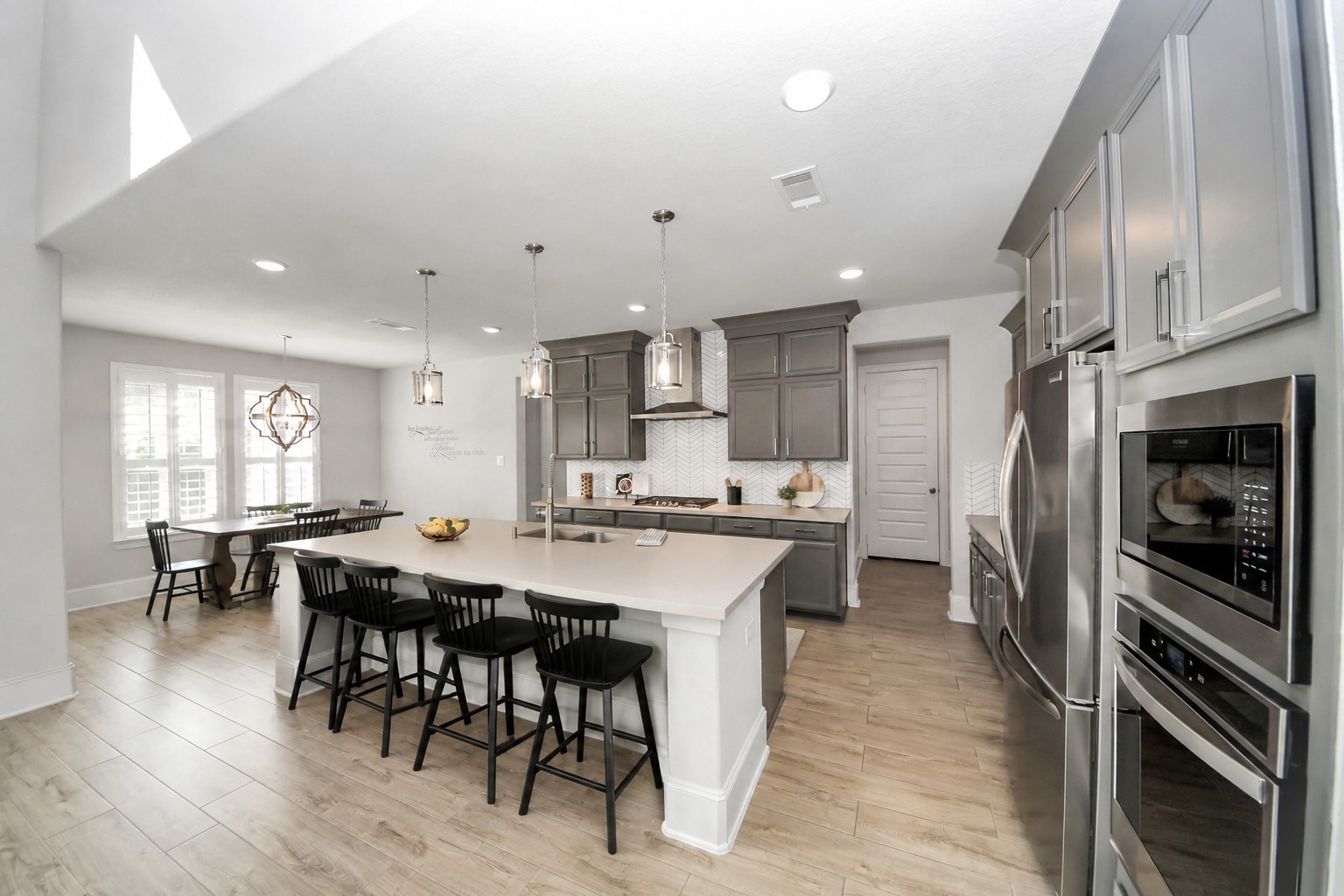 Bright and spacious kitchen with modern stainless steel appliances, a large center island with seating, and elegant pendant lighting.
