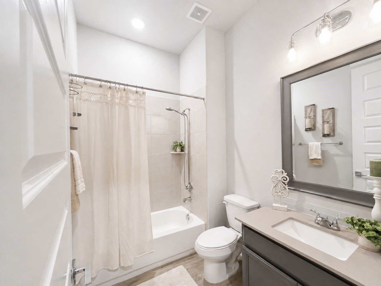A secondary bathroom found off the downstairs secondary bedroom with updated lighting fixture, and a shower/tub combo.