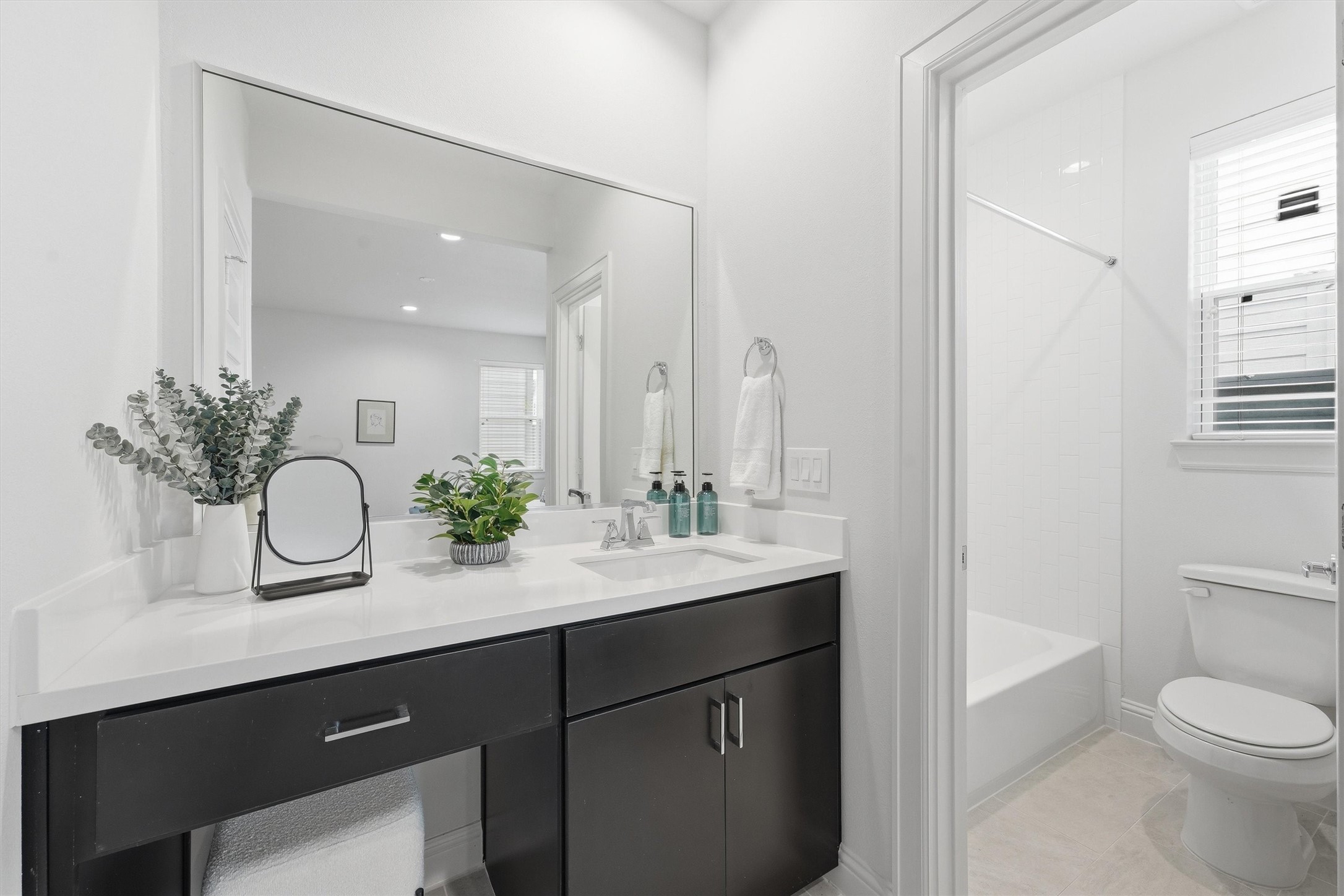 Sleek and inviting, this guest bathroom boasts a modern vanity, ample lighting, and a pristine shower area, perfectly blending style and comfort for your visitors.