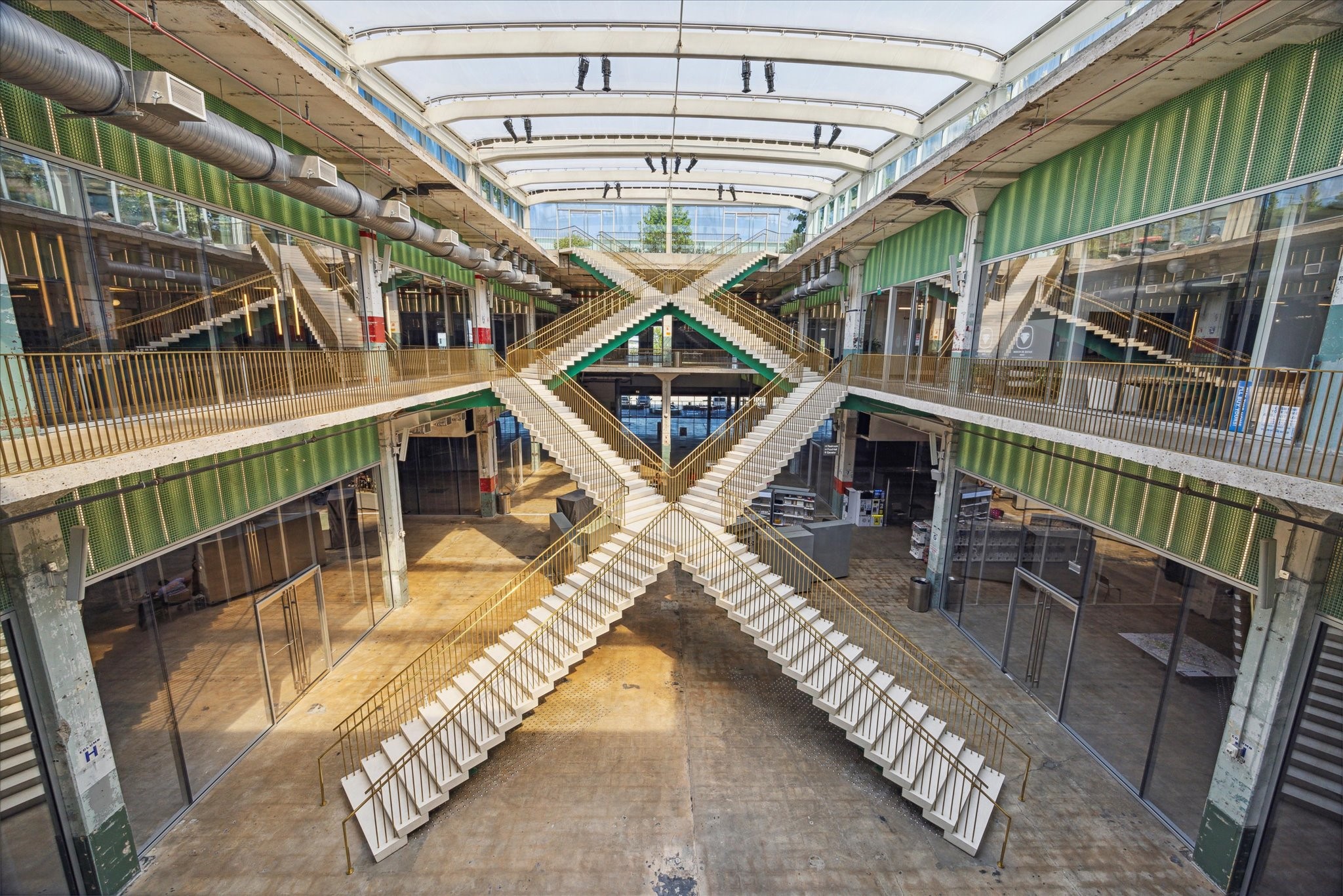 A modern, open-concept atrium nearby with striking intersecting staircases, surrounded by glass walls and industrial accents, offering a unique architectural experience.