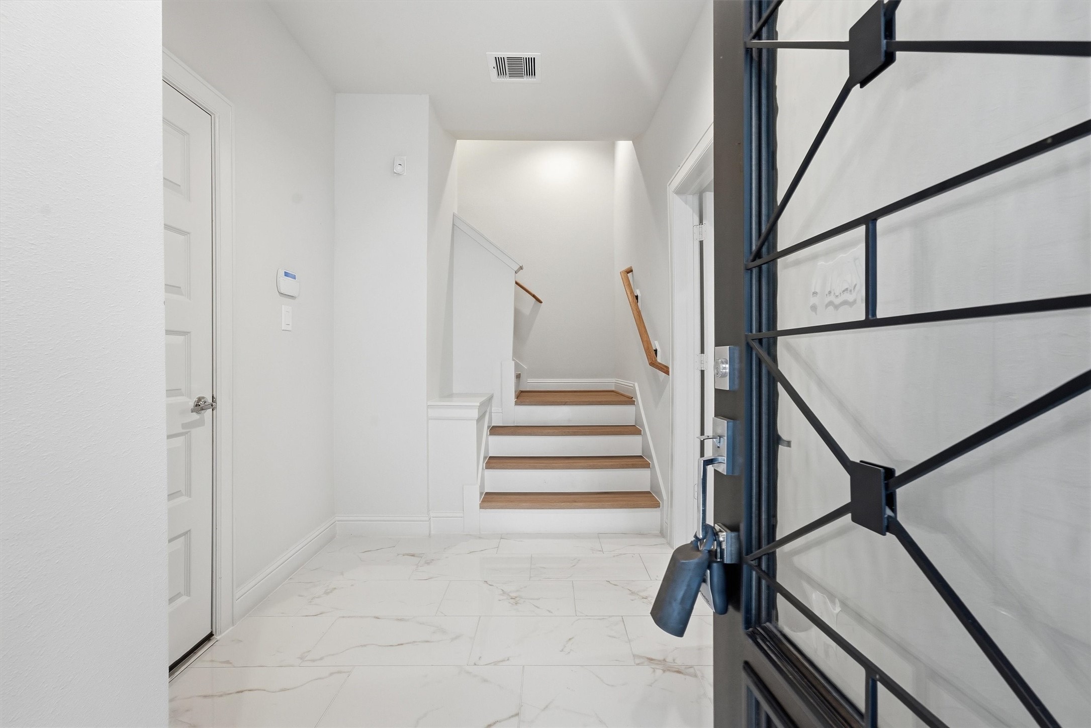 Enter a realm of elegance through this bright and inviting entrance, where sleek tile flooring and a welcoming staircase set an exquisite tone for the home.