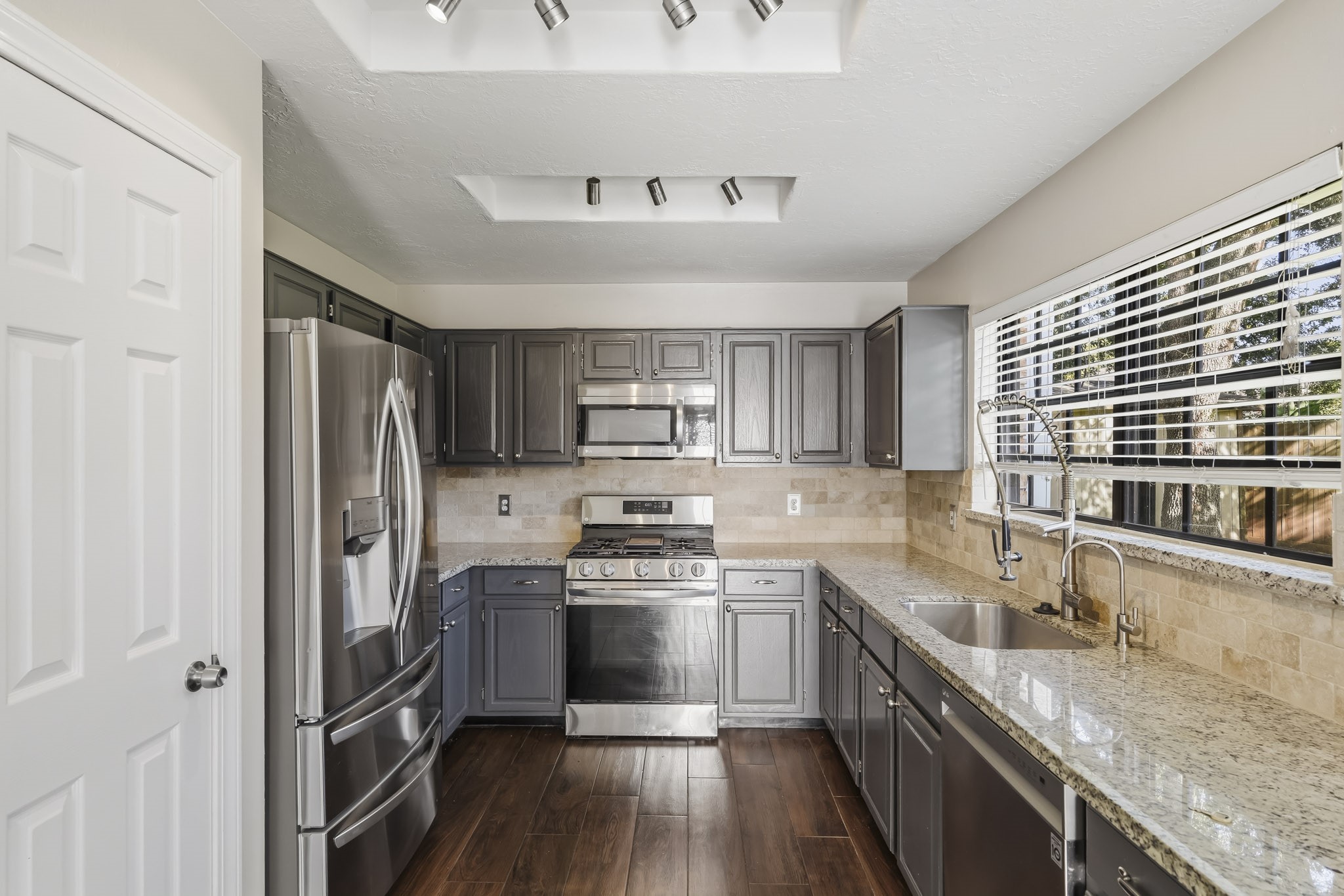 The kitchen includes granite countertops, stainless steel appliances, abundant cabinetry, and a tile backsplash, creating a functional and inviting space for everyday dining and entertaining.