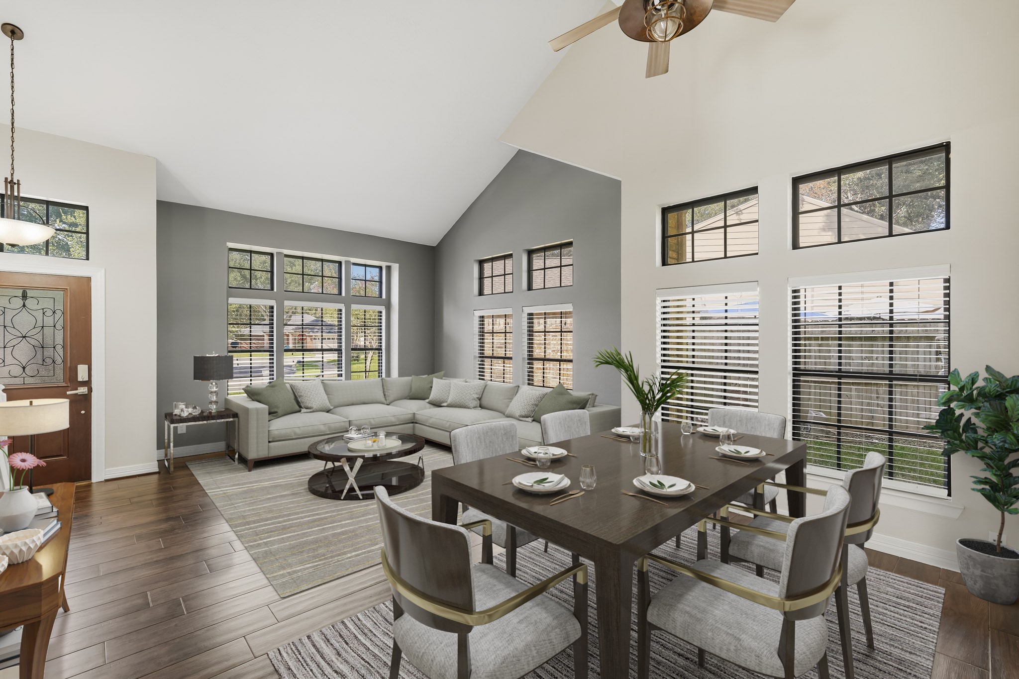 Virtually Staged: This bright, open living and dining area features soaring vaulted ceilings, warm wood-look flooring, and an abundance of natural light from multiple large windows.