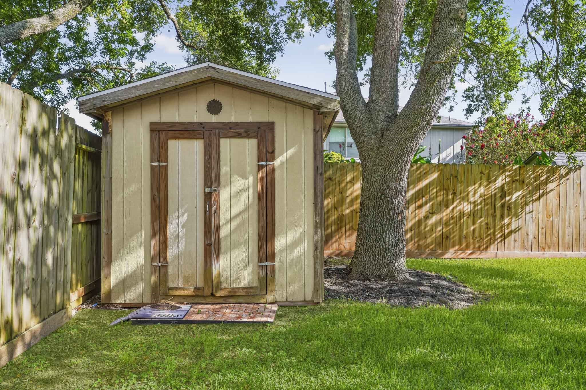 This spacious backyard includes a convenient storage shed, perfect for keeping lawn equipment, tools, pool supplies, and outdoor essentials organized.