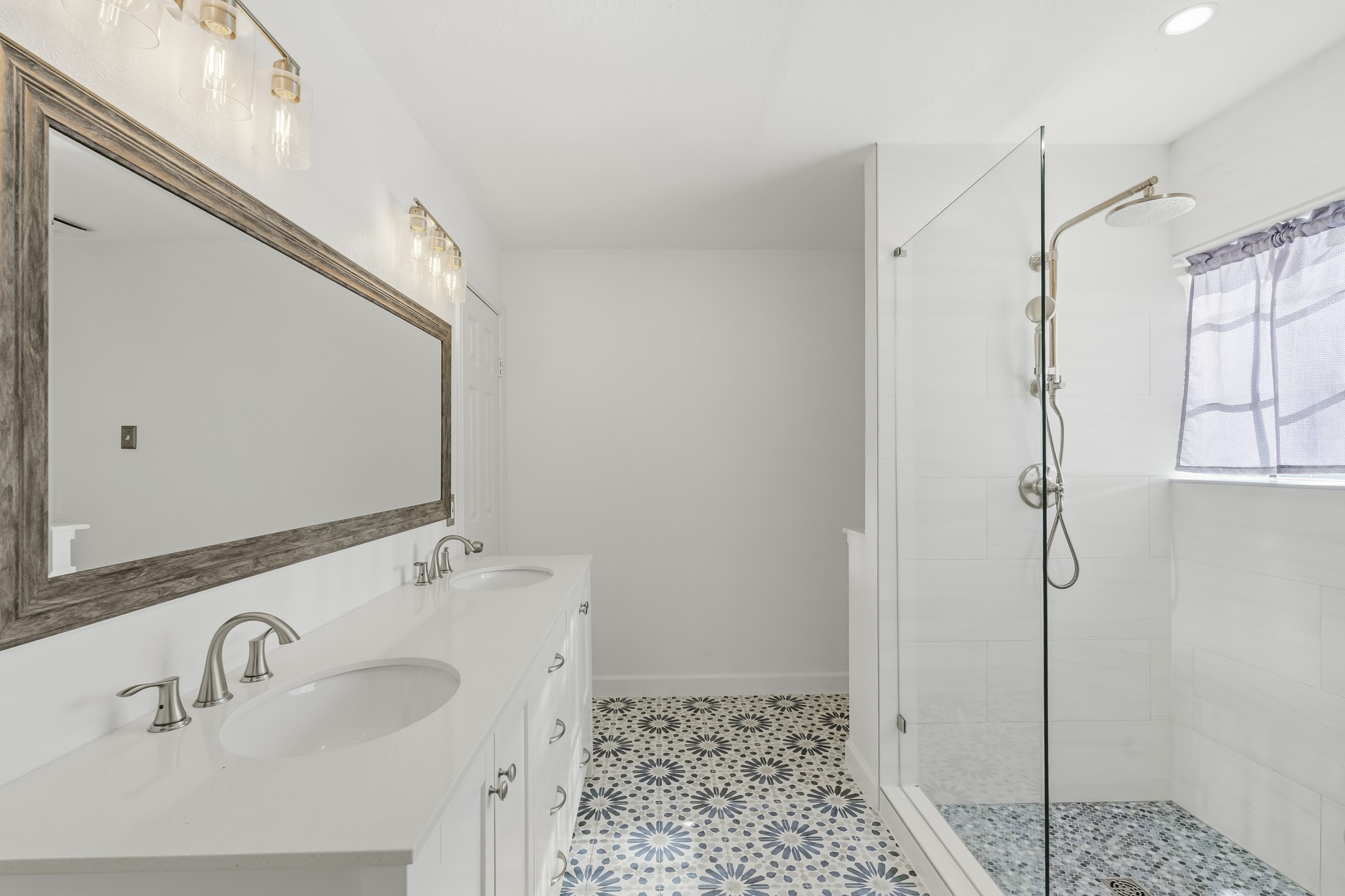 This beautifully updated primary bathroom features a spacious dual-sink vanity with abundant storage and an oversized framed mirror.