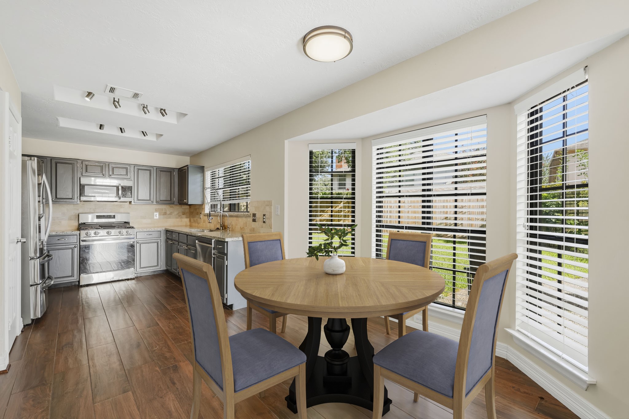 Virtually Staged: This bright breakfast area flows seamlessly into the kitchen and features warm wood-look flooring with a large bay of windows that fills the space with natural light and offers views of the backyard.