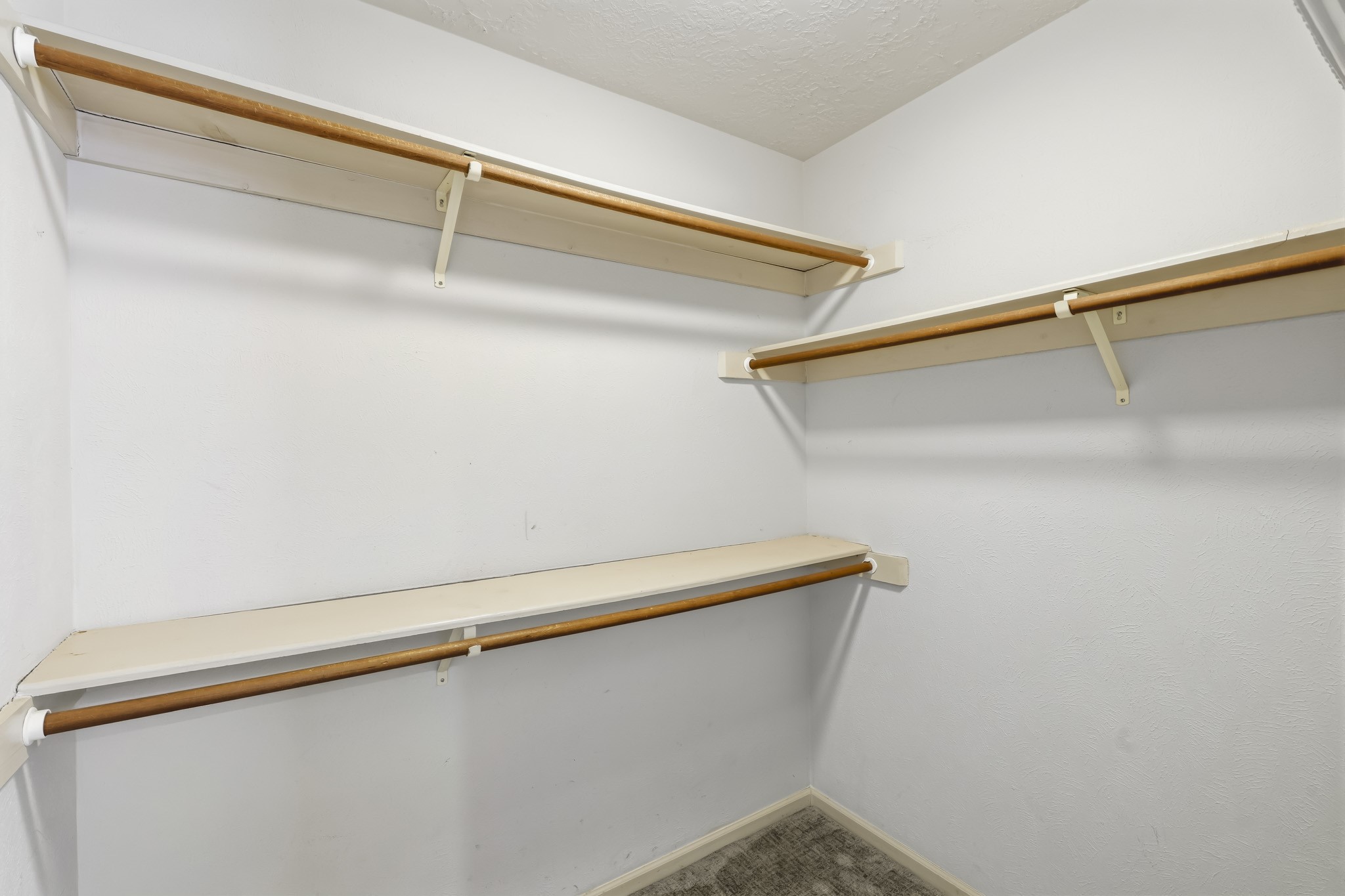 One of two master closets. This spacious walk-in closet offers abundant storage with multiple hanging rods and built-in shelving along several walls.