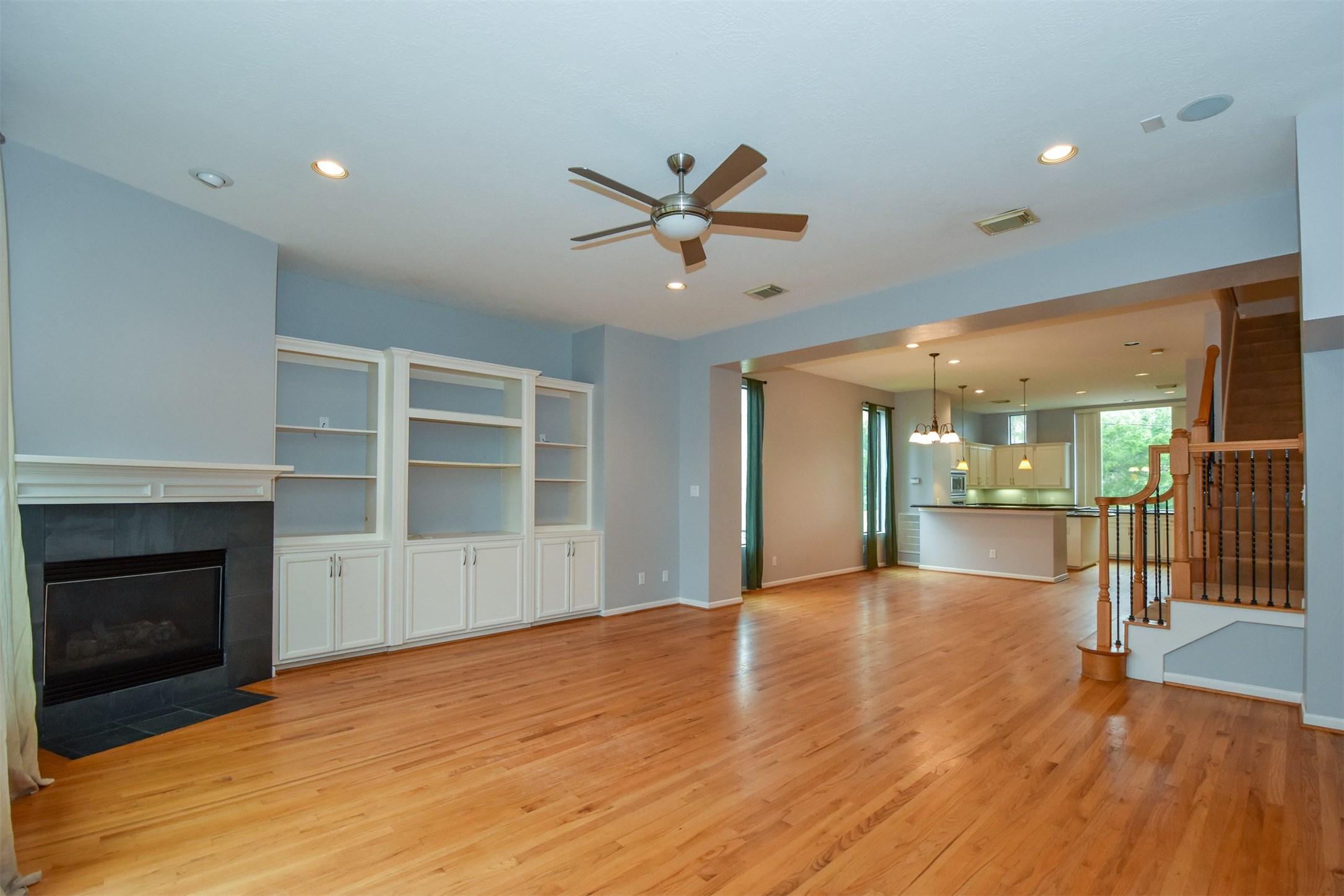 Open family room with fireplace and cabinets/built-ins, recessed lights