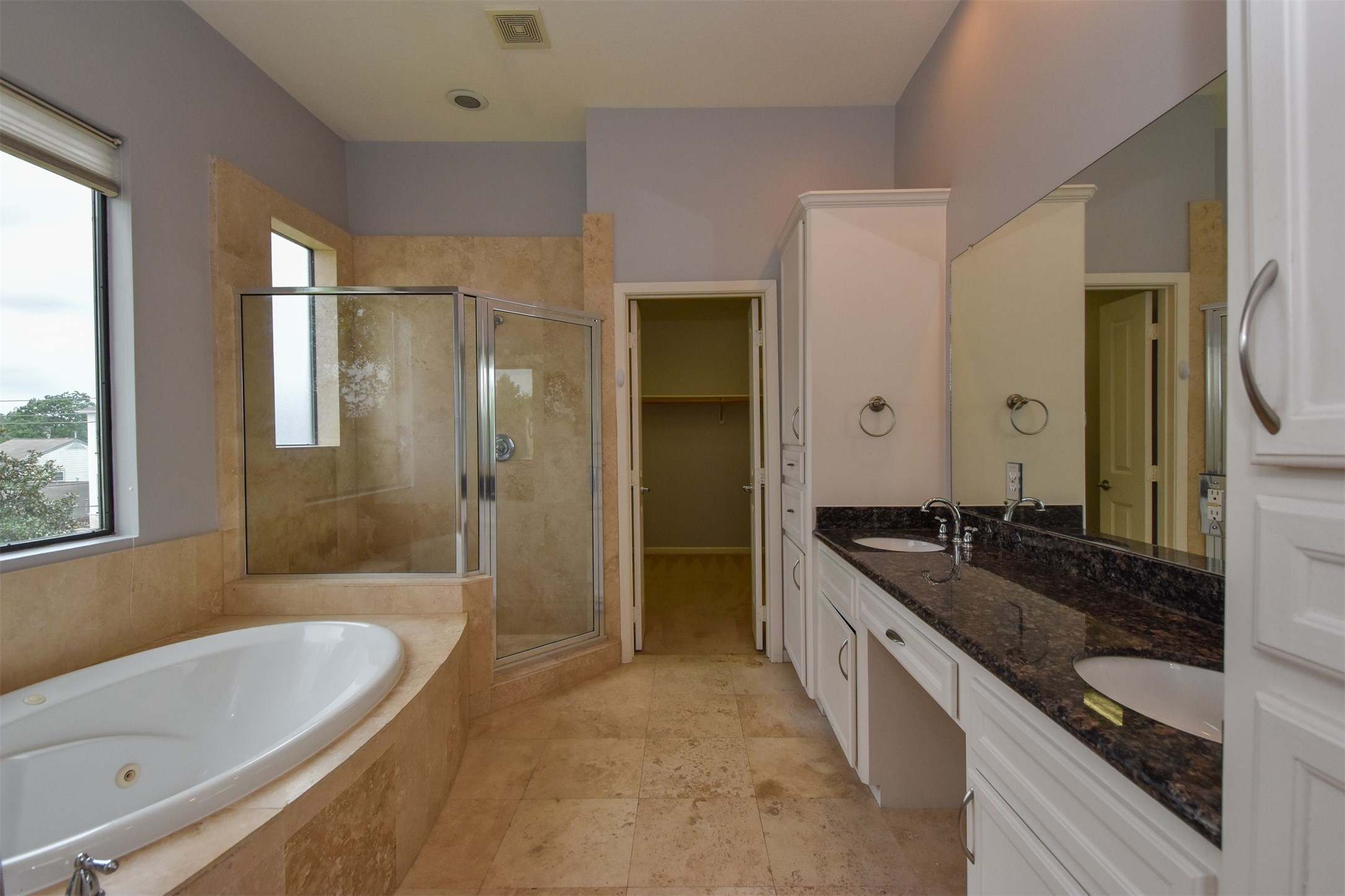 Master bathroom with double vanities, travertine floors, jacuzzi tub and walk-in shower