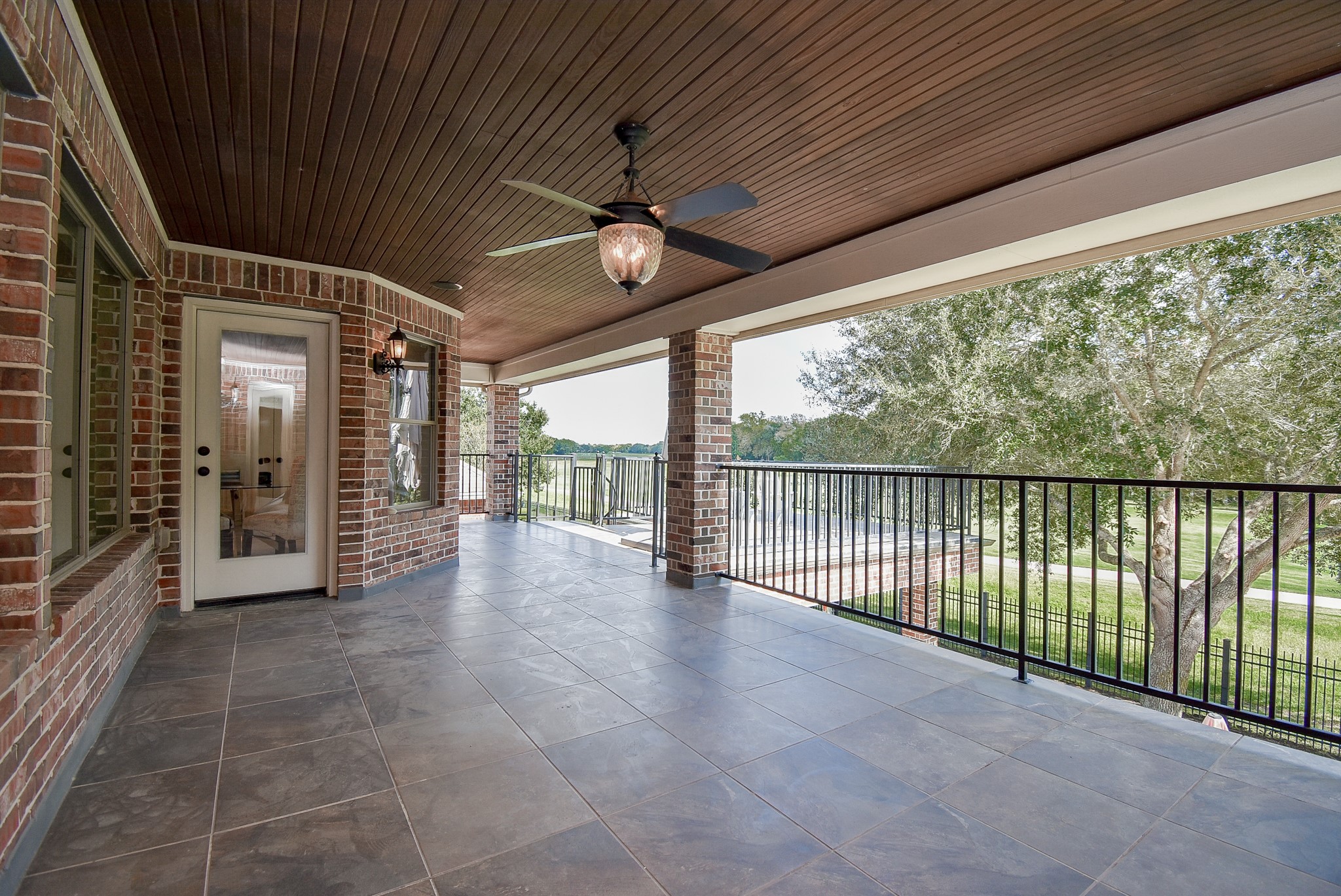 Covered balcony with bead board ceiling, tile flooring and endless views to the Meadow Brook Farms golf course.