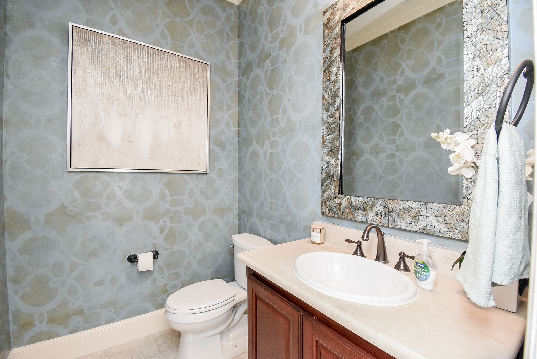 The powder bath has customized walls. Tile floors and accent mirror.